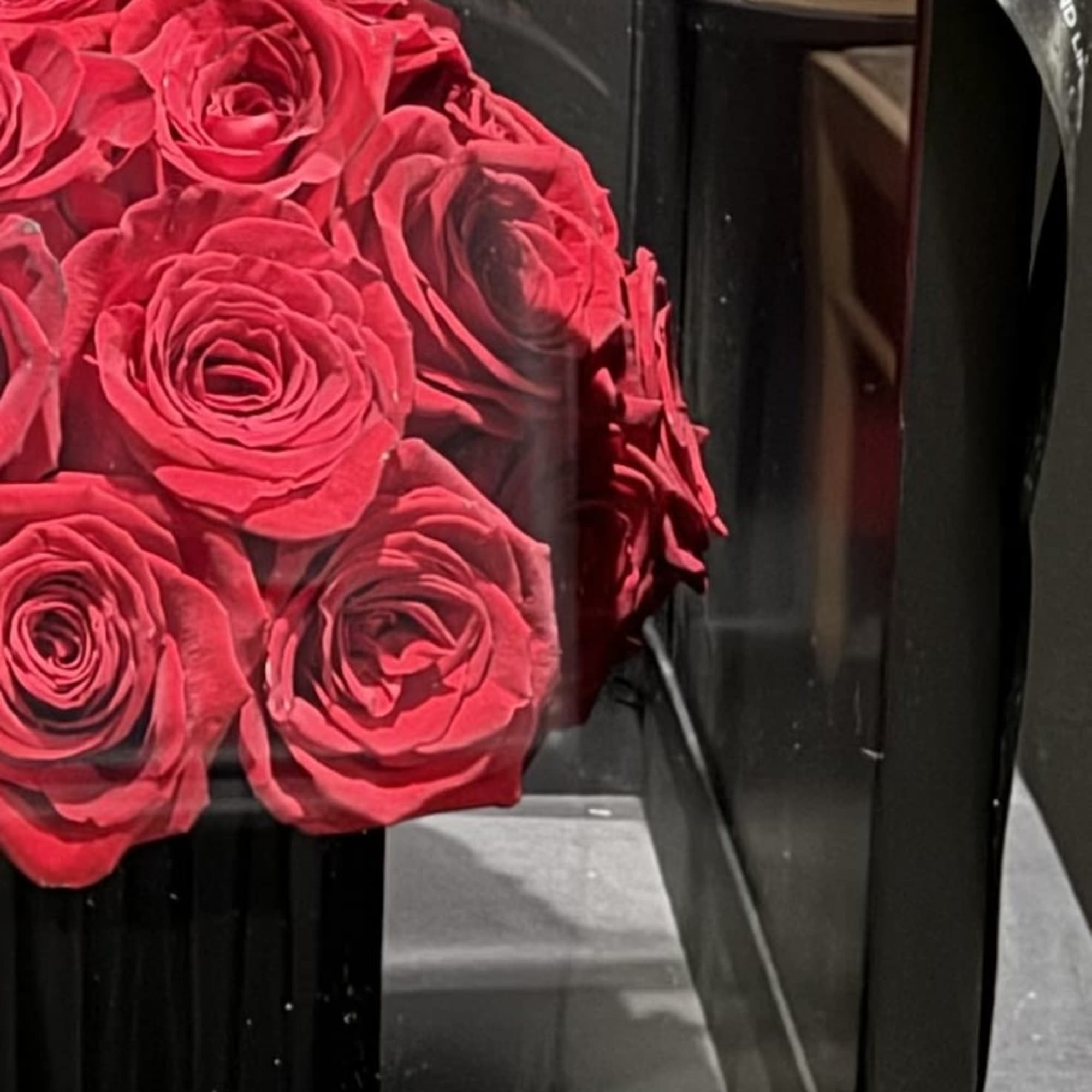 Red roses in a black square gift box with a ribbon bow
