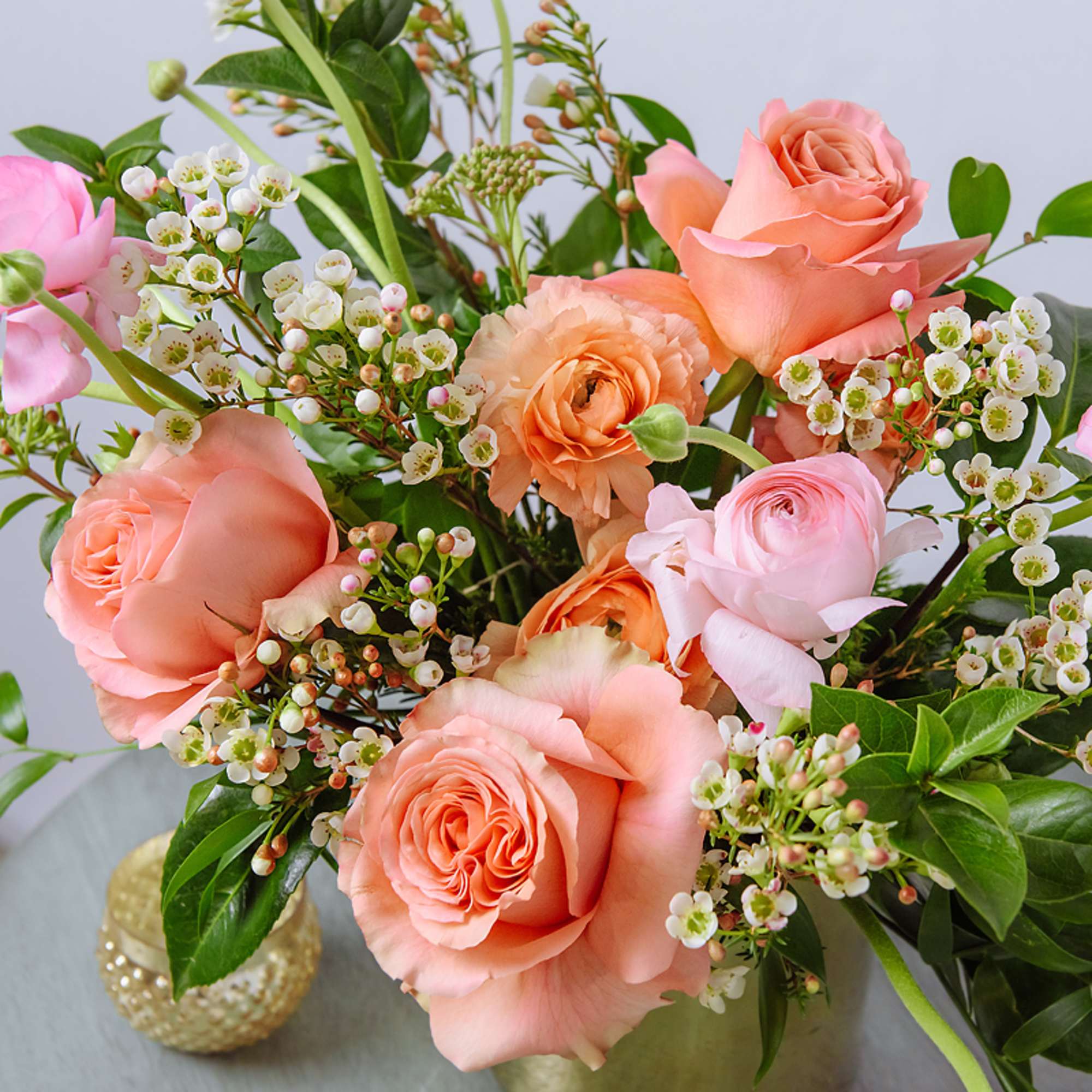 Peach and pink roses with white filler flowers in a vase