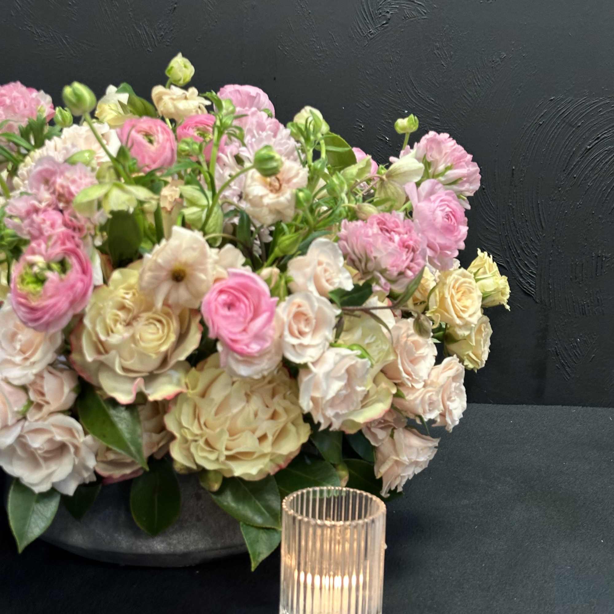 Pink and cream flower arrangement with a glass candle holder
