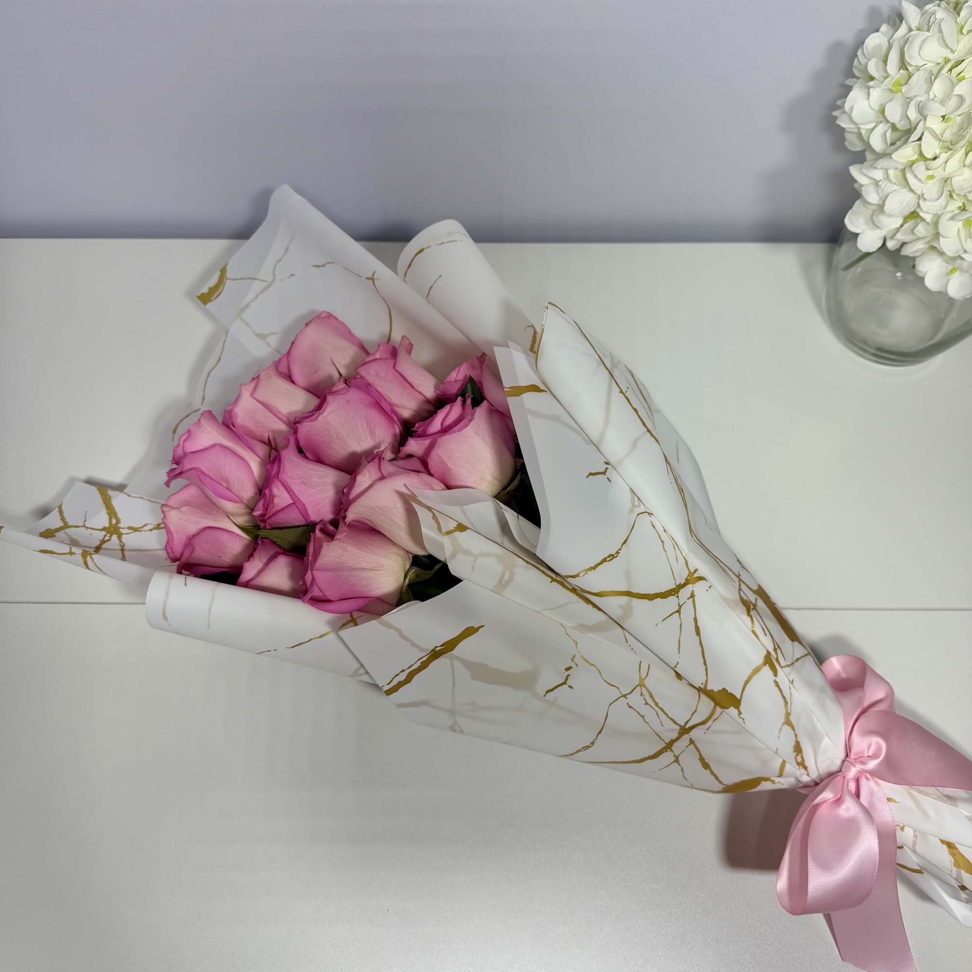 Delicate blush roses beautifully wrapped in elegant white and gold paper, thoughtfully