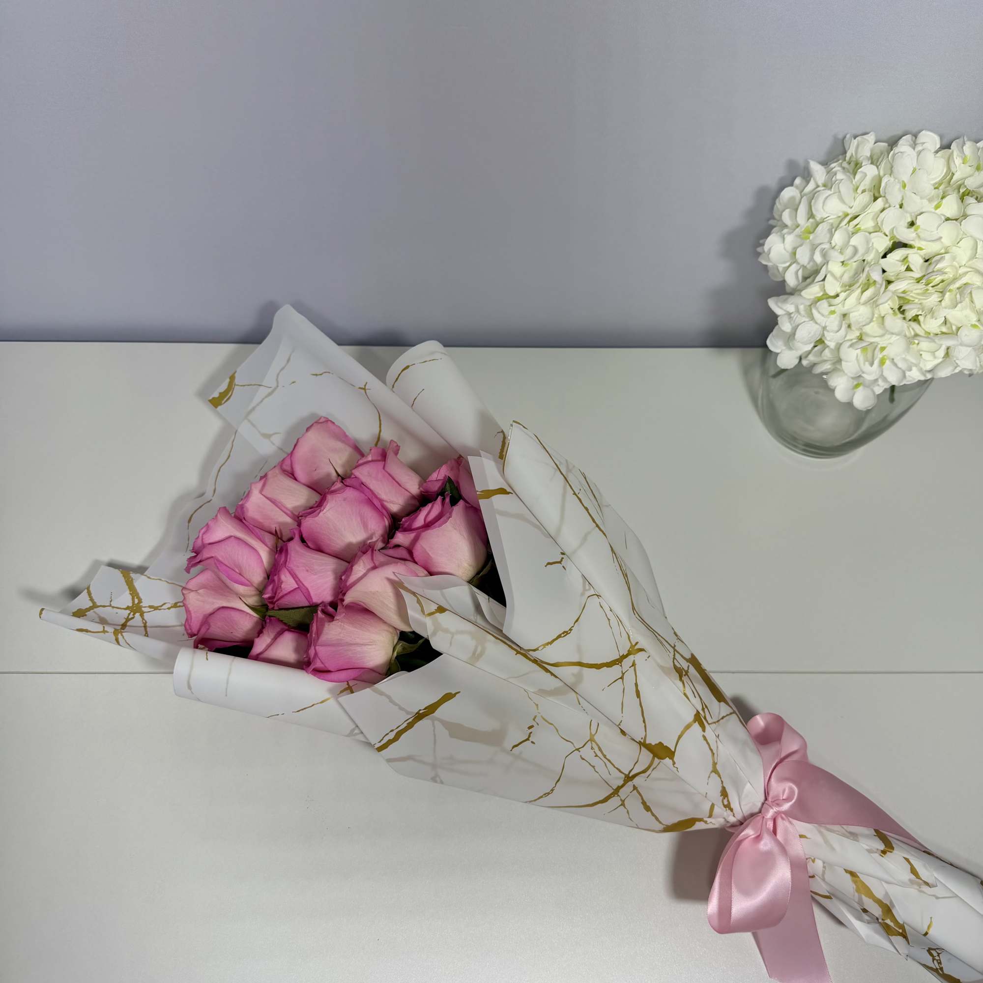 Delicate blush roses beautifully wrapped in elegant white and gold paper, thoughtfully