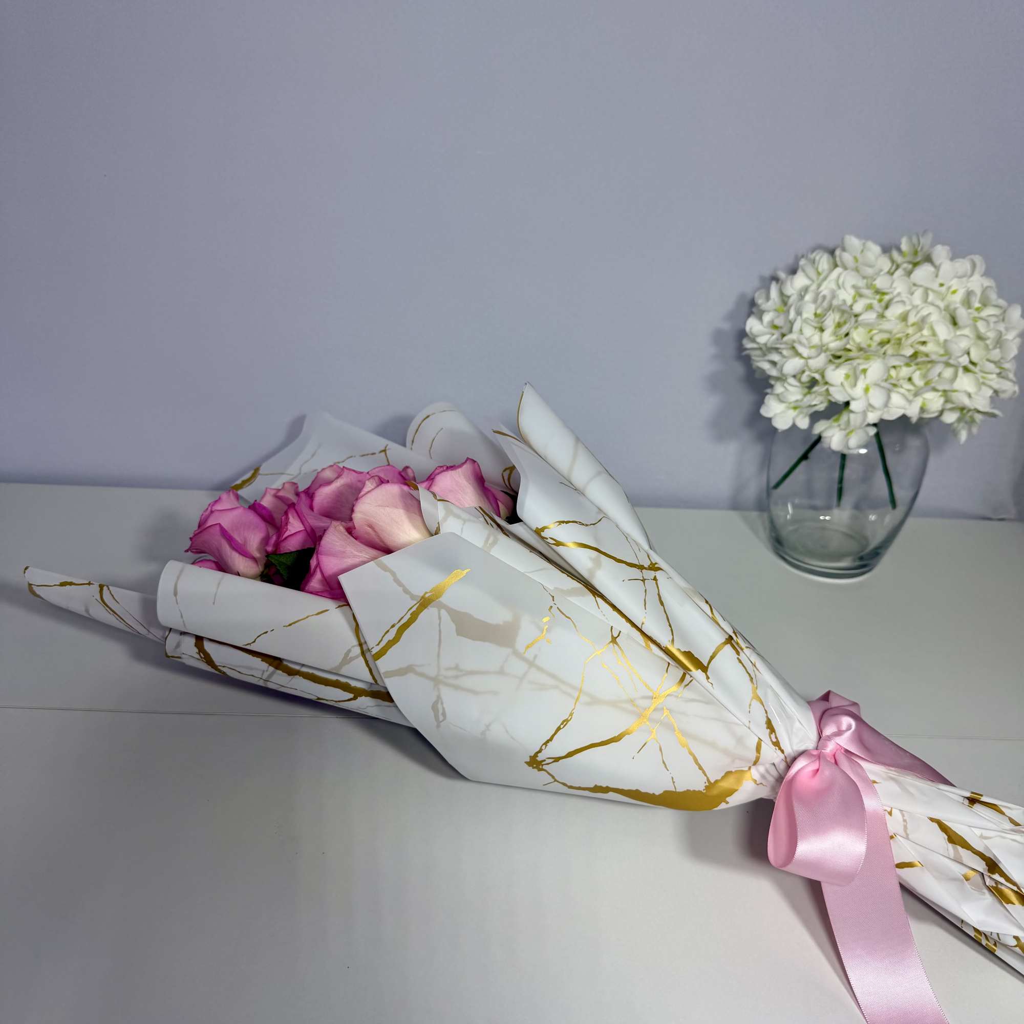 Delicate blush roses beautifully wrapped in elegant white and gold paper, thoughtfully