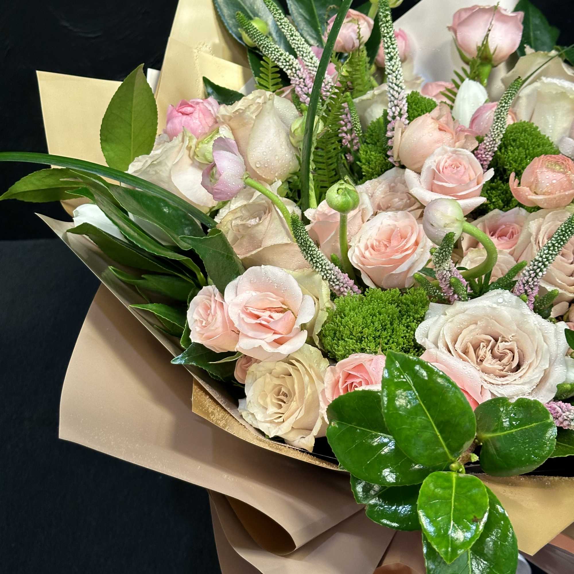 Bouquet of pale pink and cream roses wrapped in tan paper