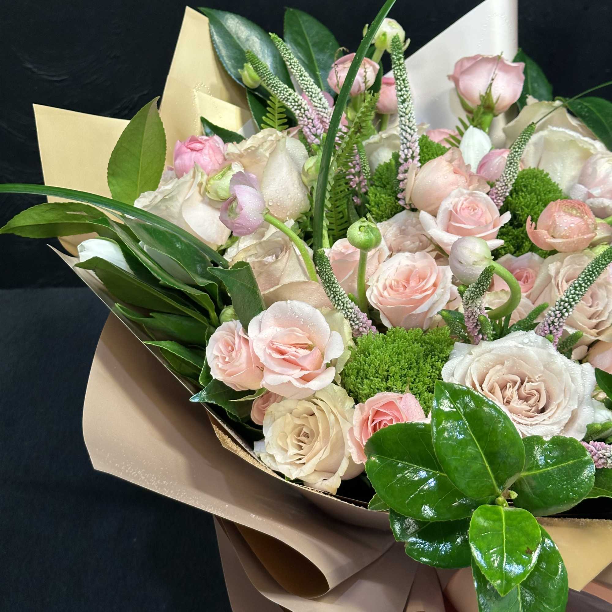 Bouquet of pale pink and cream roses with green accents in paper wrap