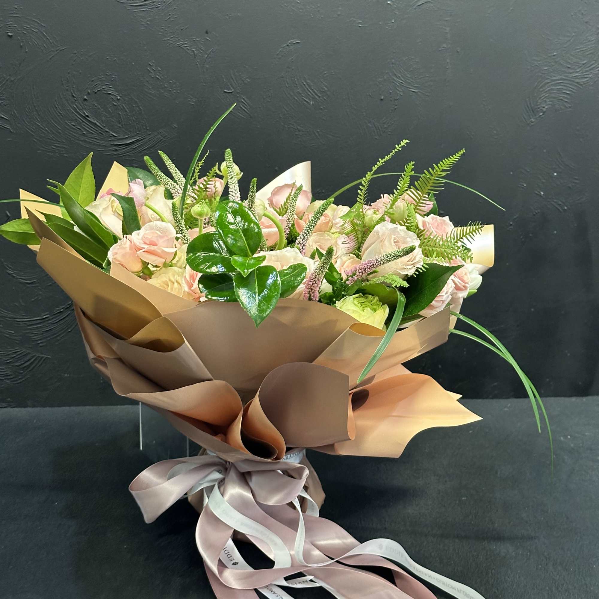 Bouquet of pale pink roses wrapped in brown paper with a ribbon
