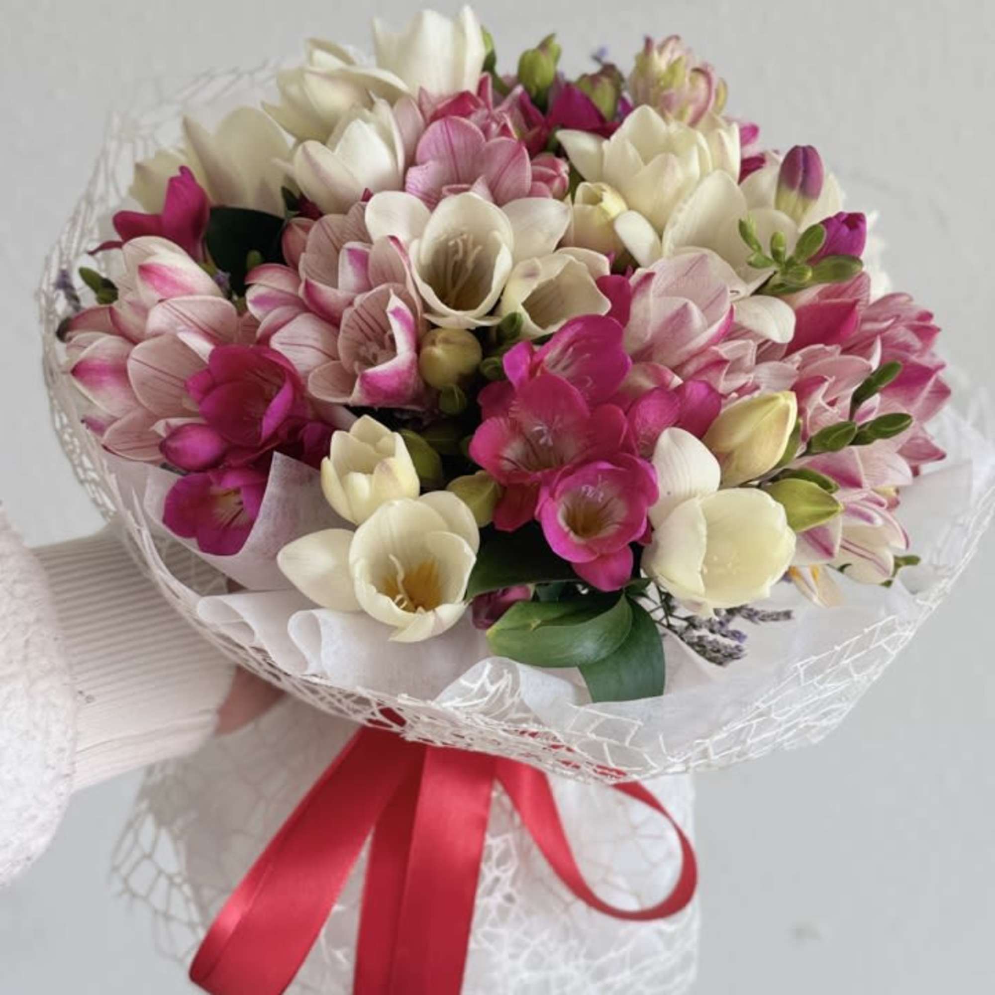 Bouquet of pink and white freesia wrapped with a red ribbon
