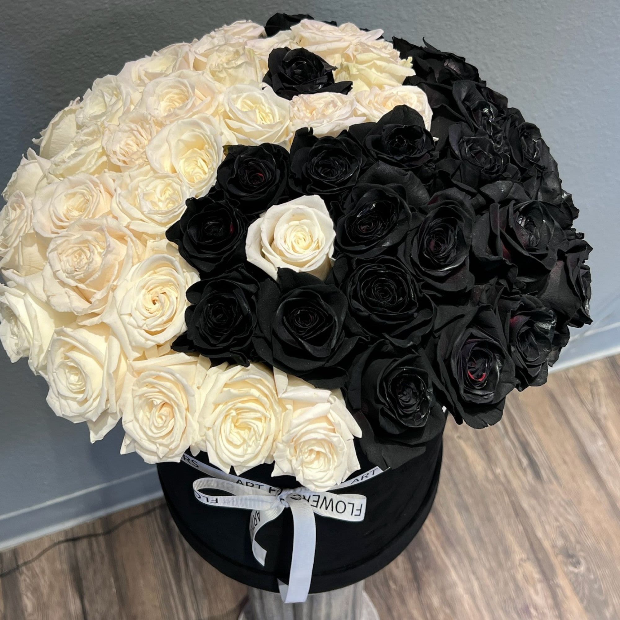Black and white rose arrangement in a round hat box