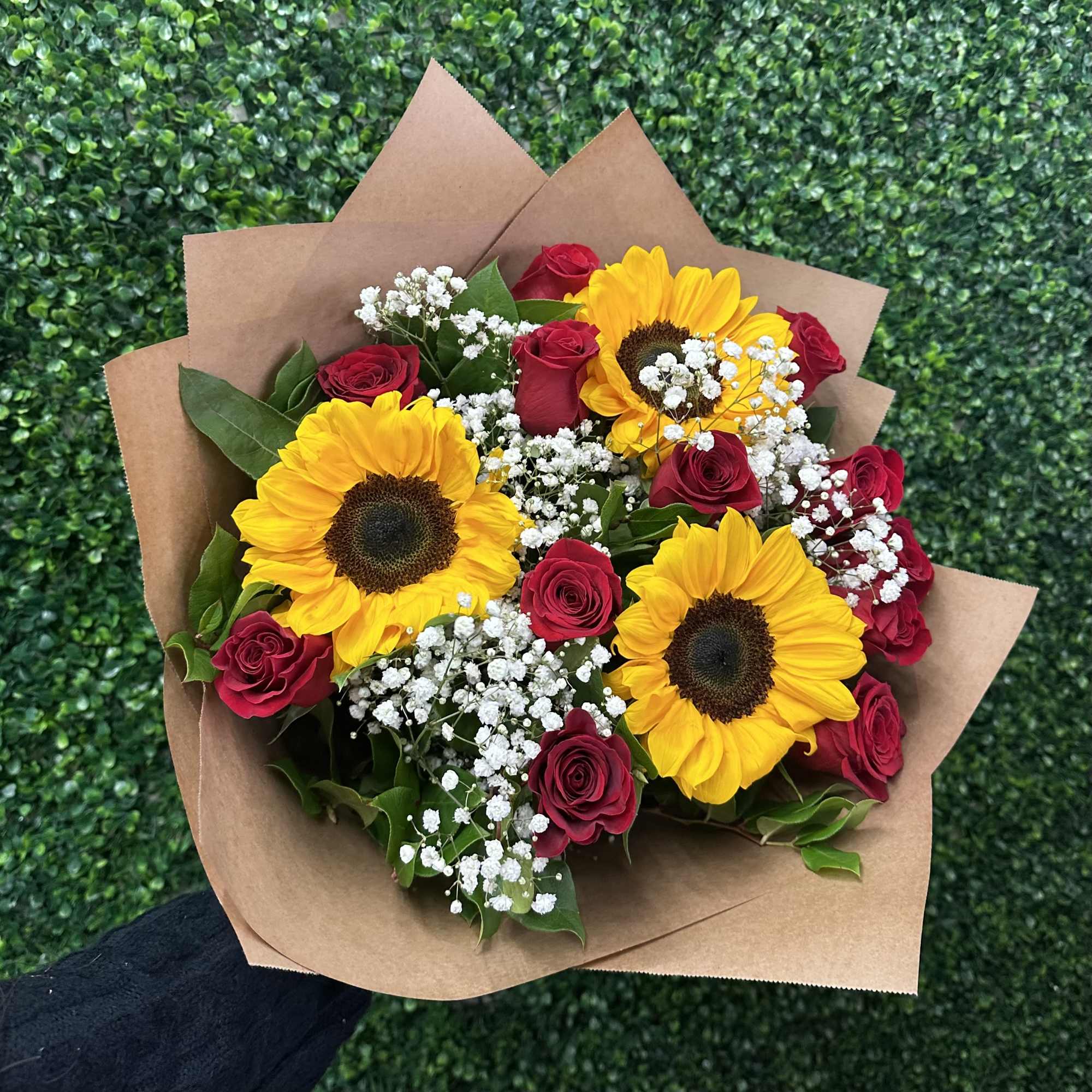 Bouquet of yellow sunflowers and red roses wrapped in brown paper