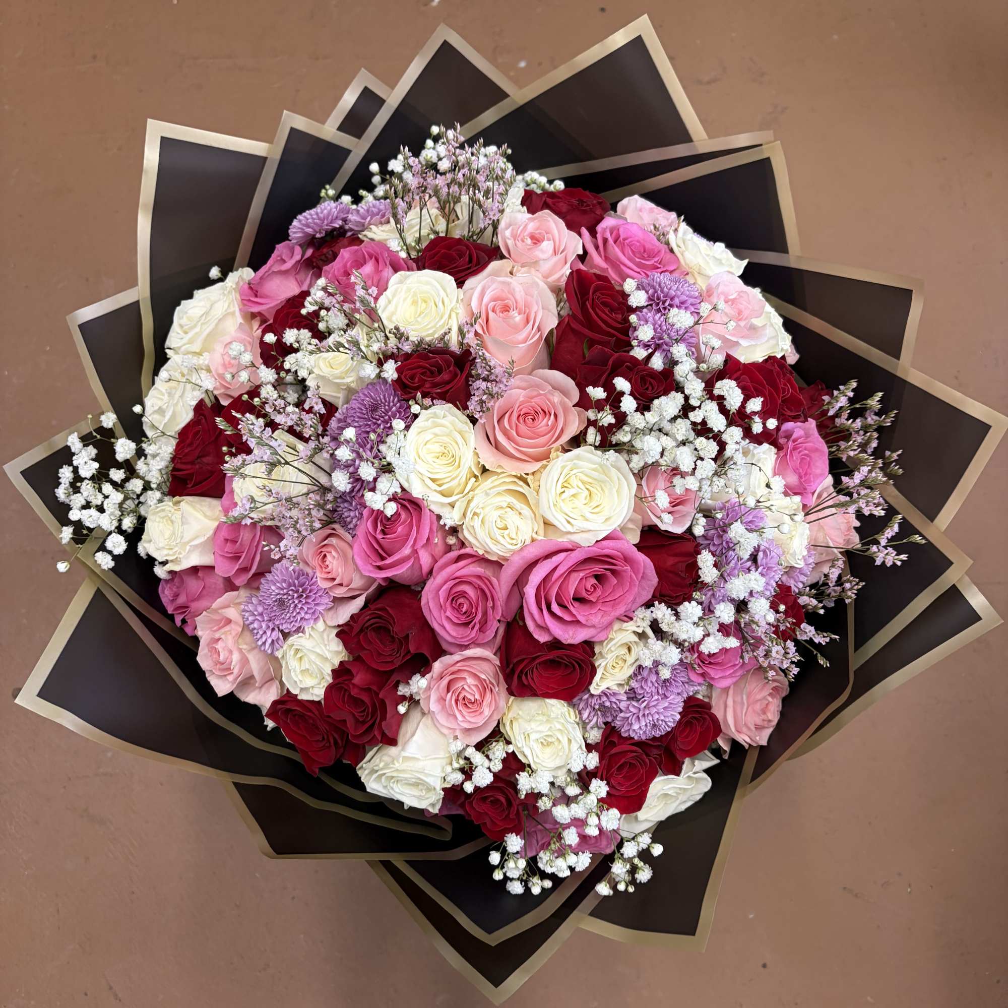 Large bouquet of pink, red, and white roses with purple accents
