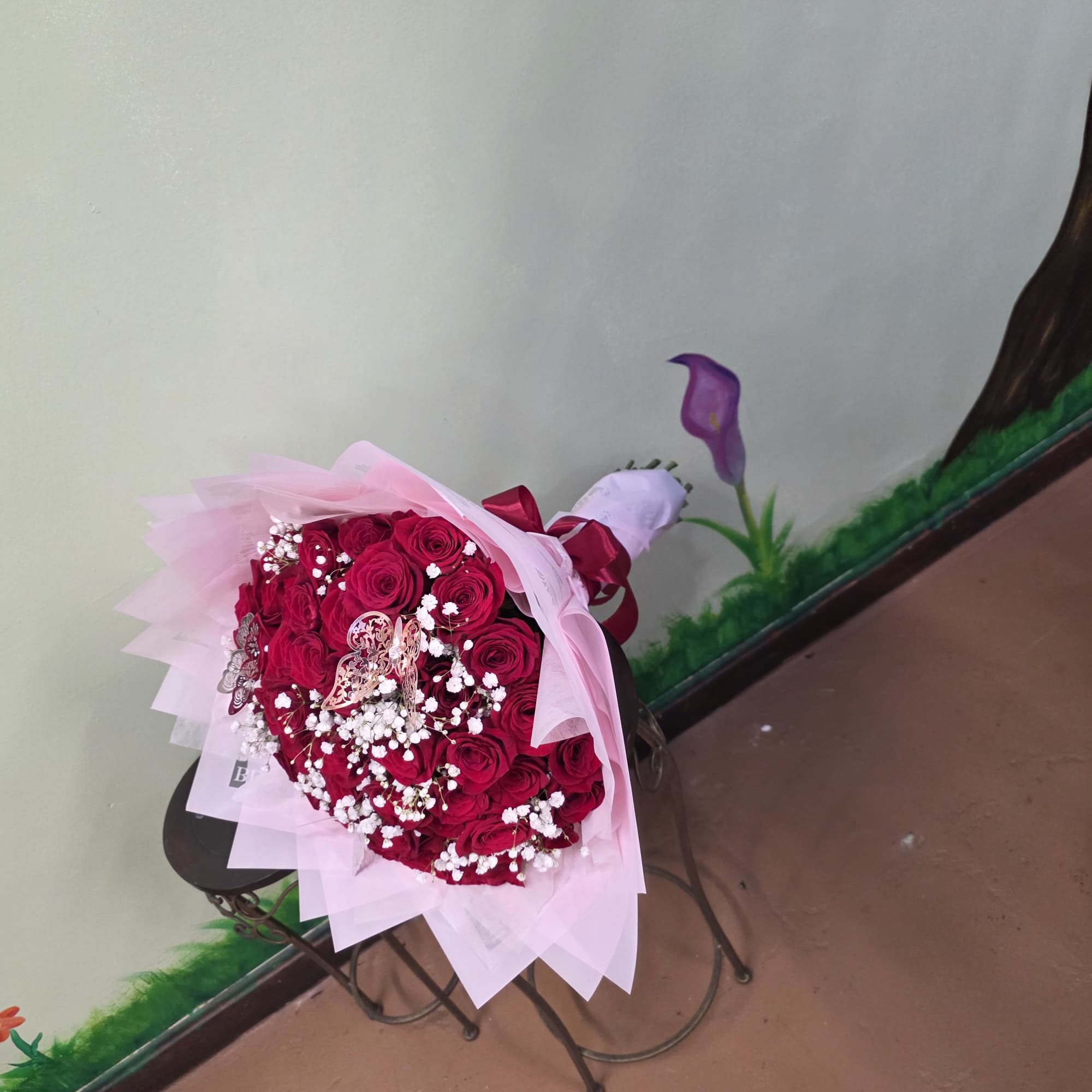 Bouquet of red roses wrapped in pink paper with white baby's breath