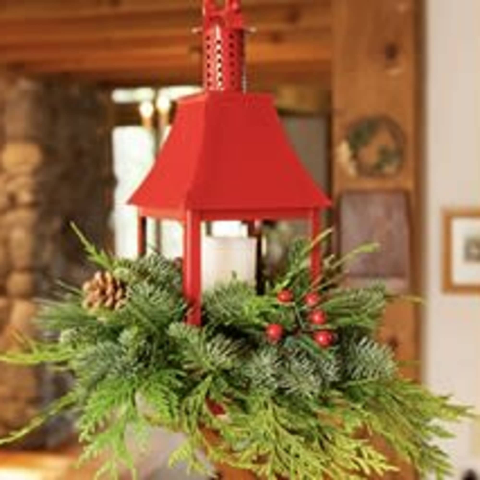 Red lantern centerpiece with evergreen and pinecone accents