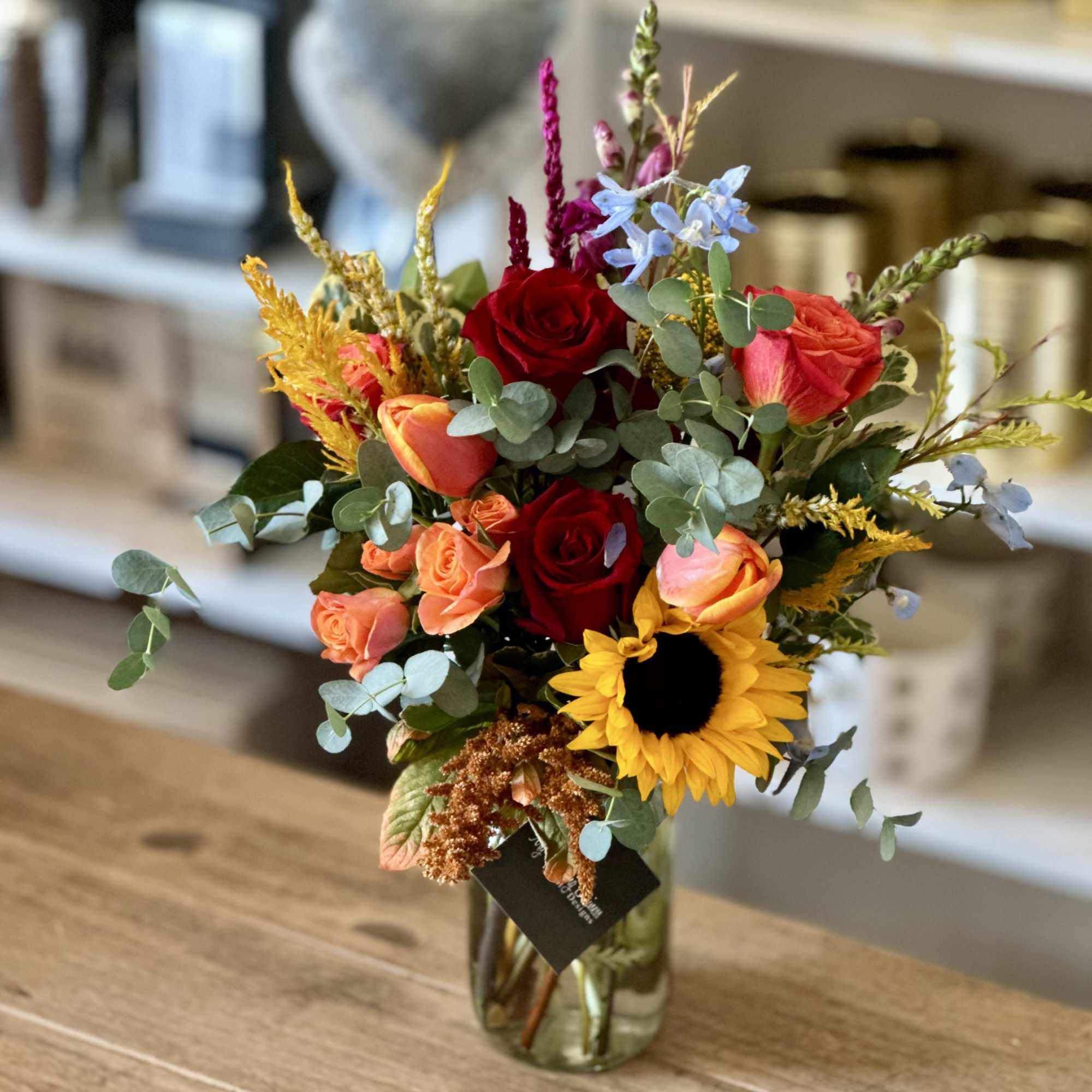 Mixed bouquet of roses and a sunflower in a glass vase