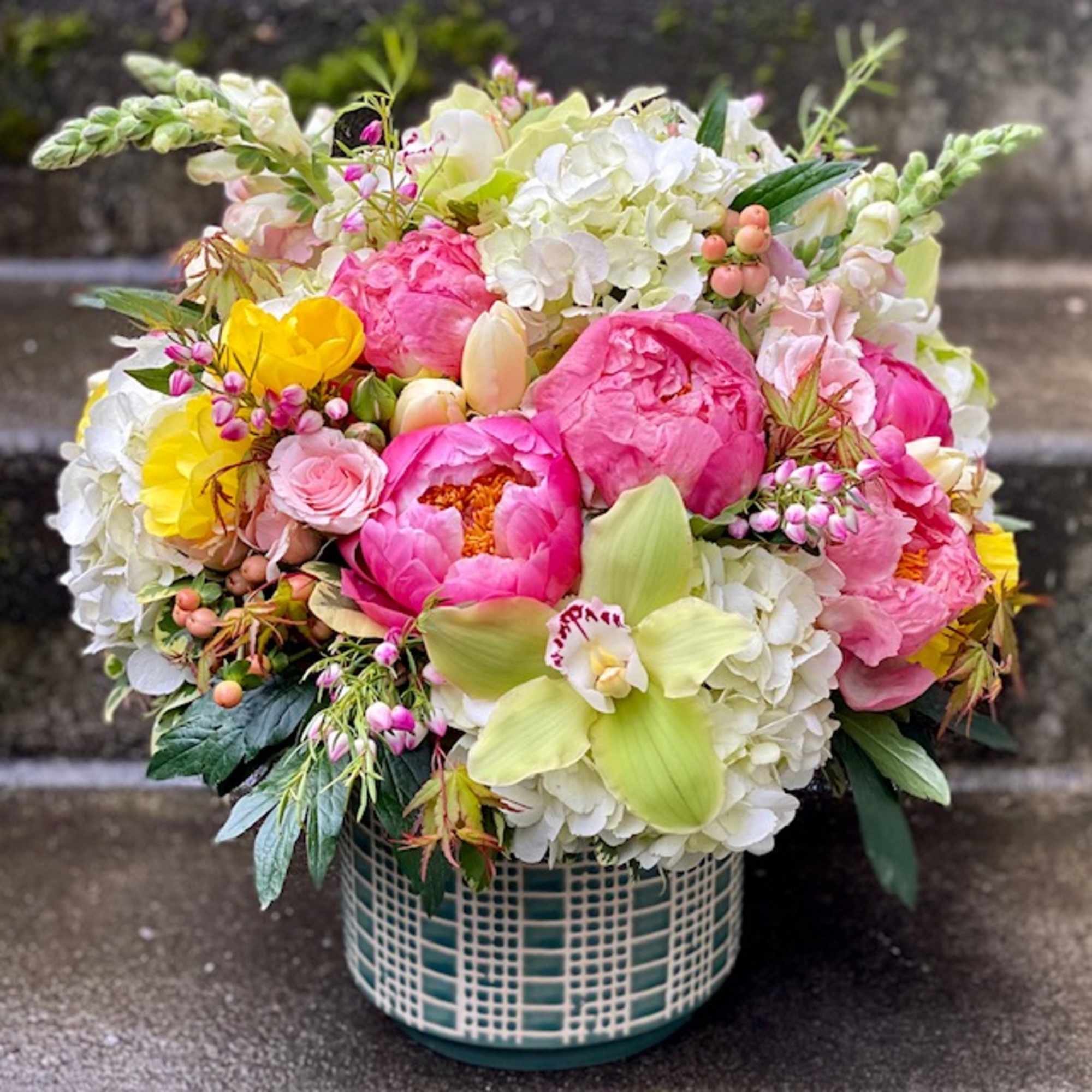 Colorful bouquet in a teal lattice vase with pink, white, and yellow blooms