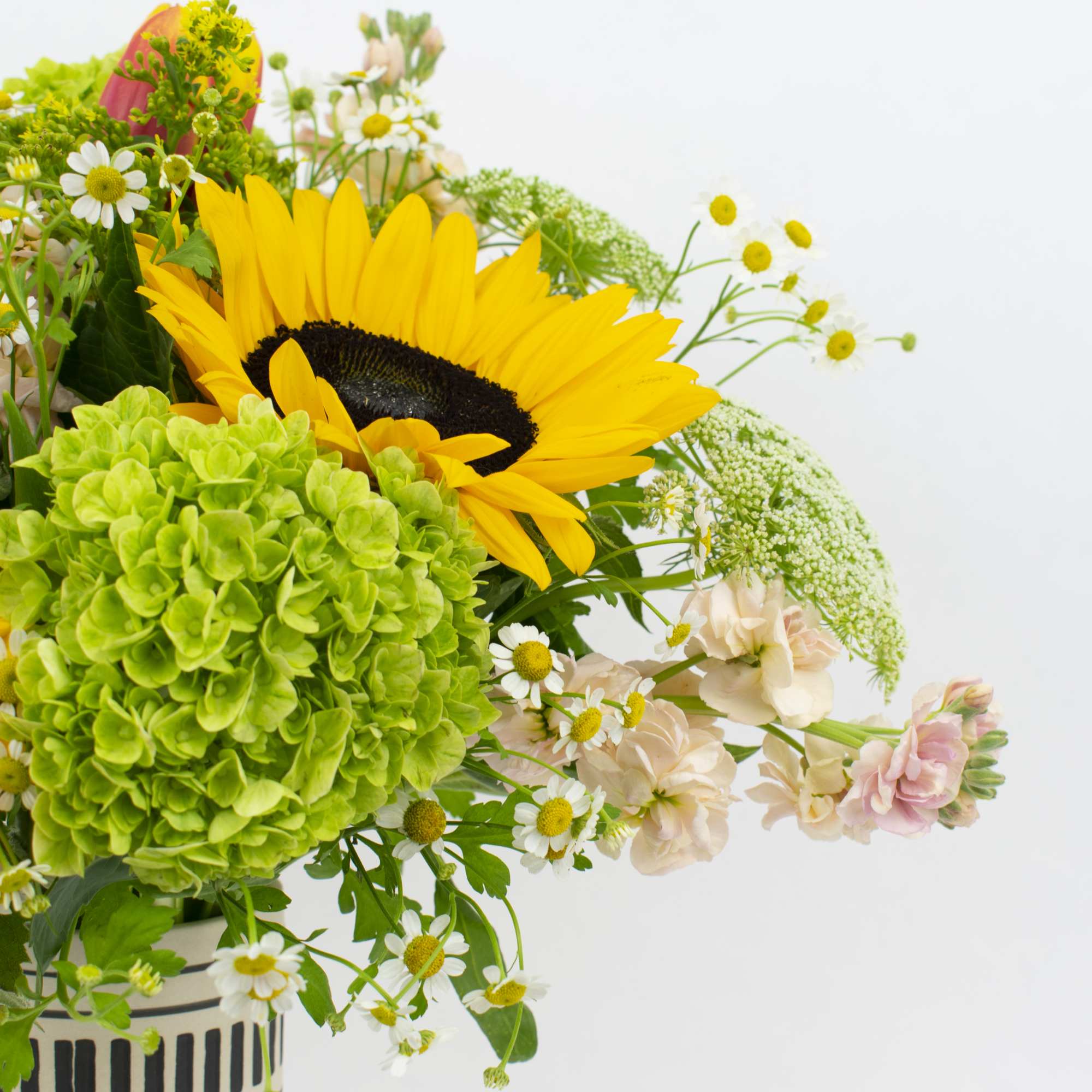 Bouquet with sunflowers, green hydrangea, and small daisies in a striped vase