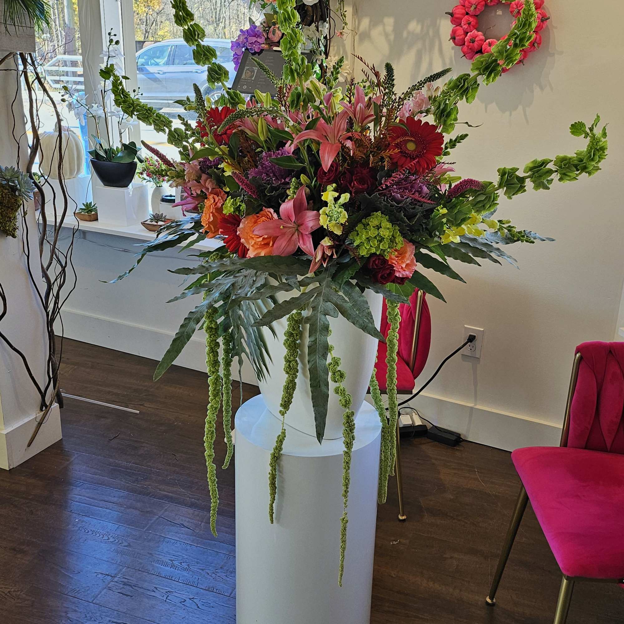 Large colorful floral arrangement in a white pedestal vase