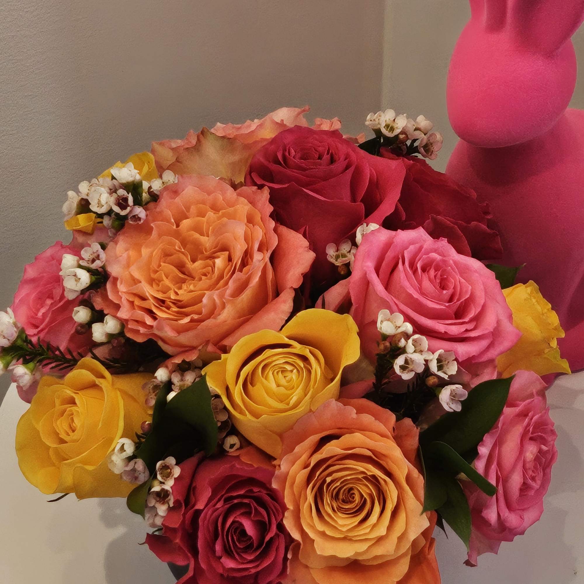 Bouquet of multicolored roses with a pink bunny figure beside it