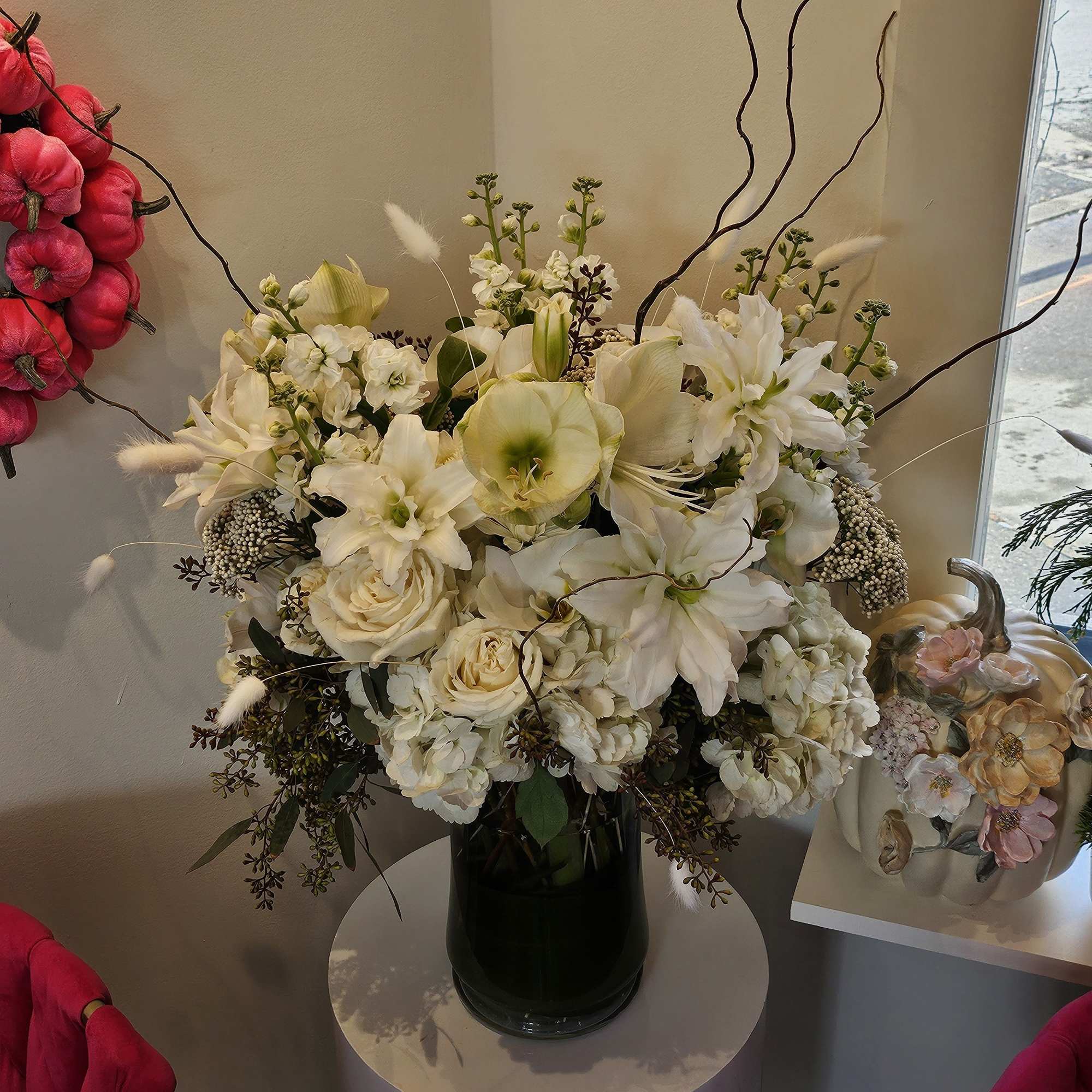 White floral arrangement in a dark glass vase with tall branches