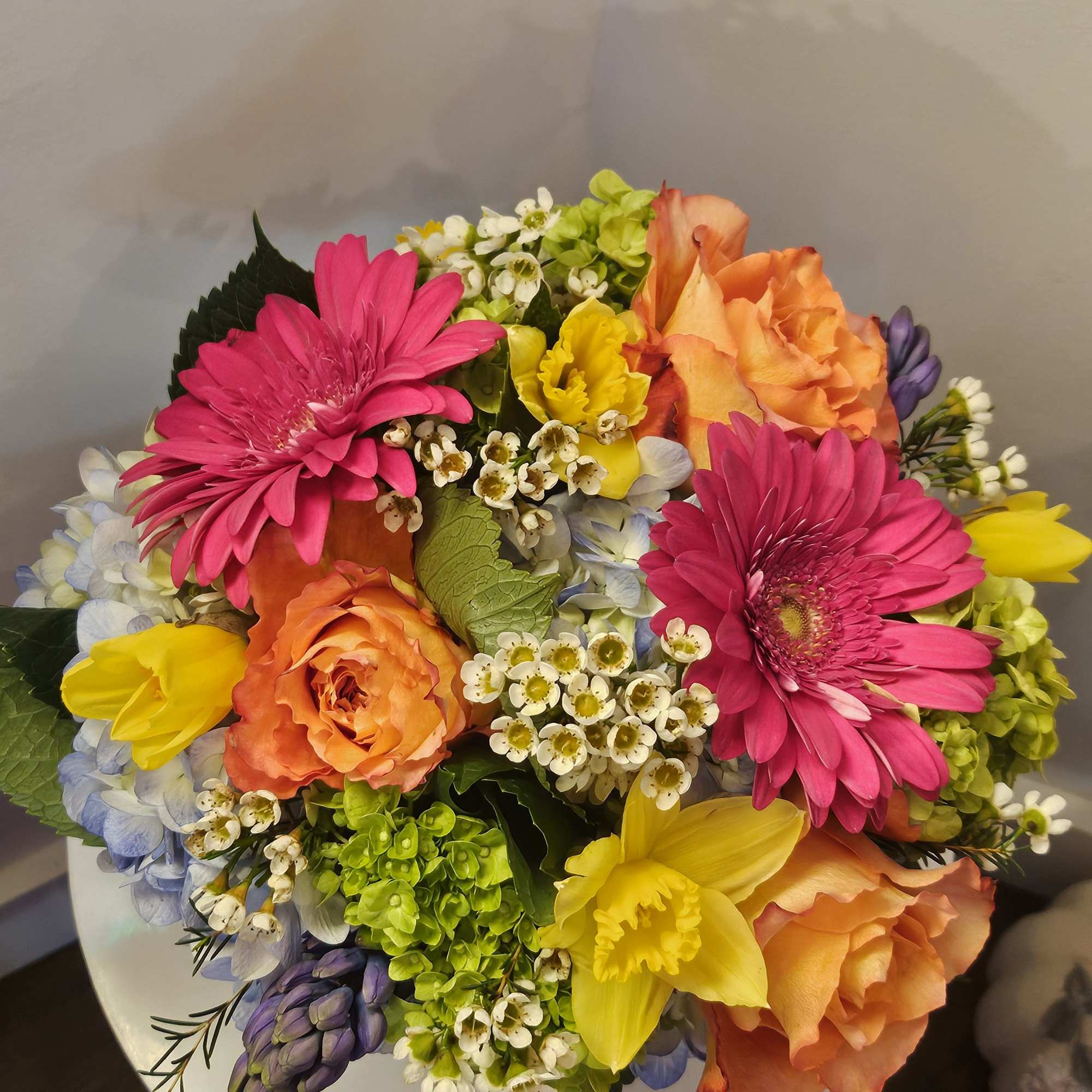 Bouquet of pink gerbera daisies, orange roses, and yellow daffodils