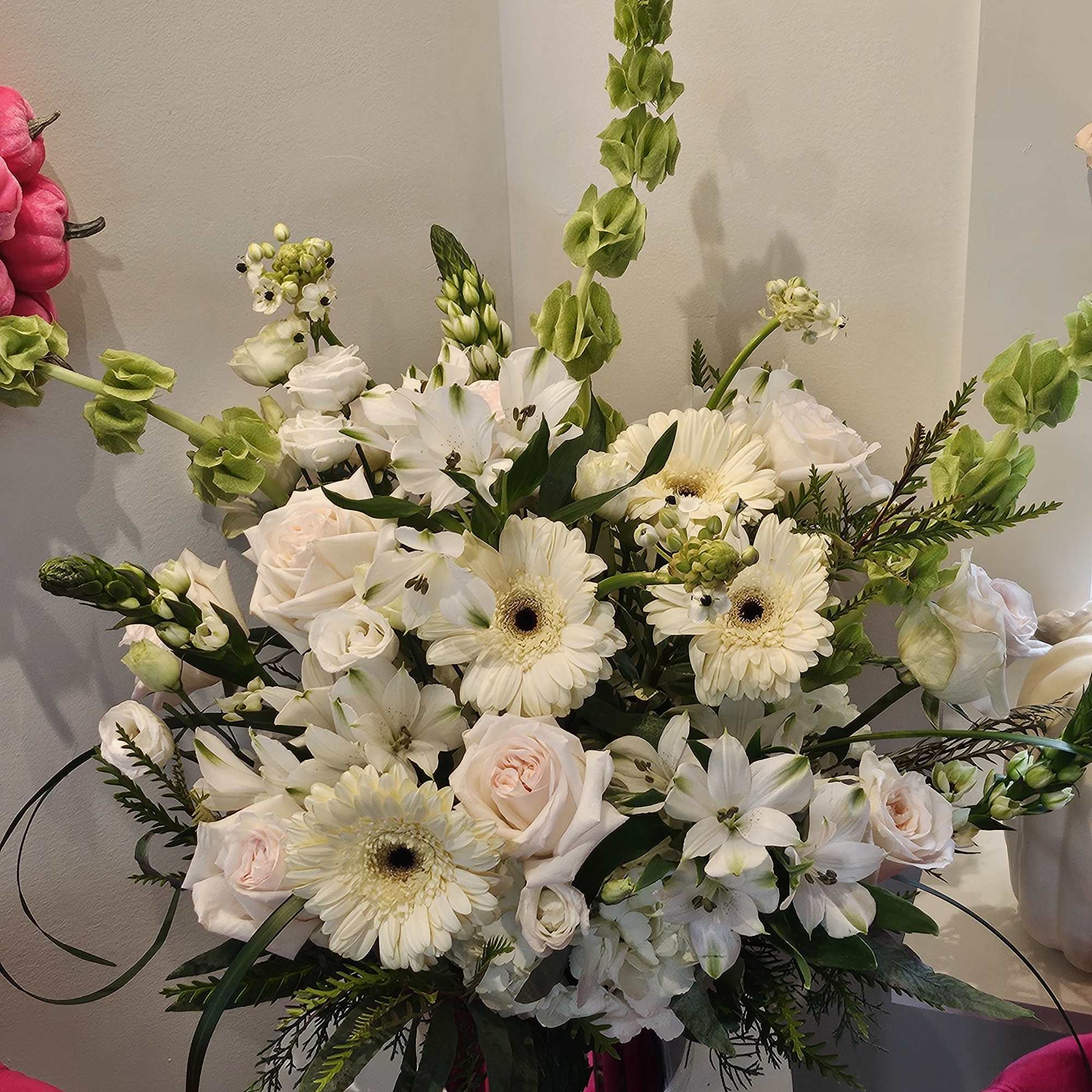 White floral arrangement with roses, gerbera daisies, and lilies in a vase