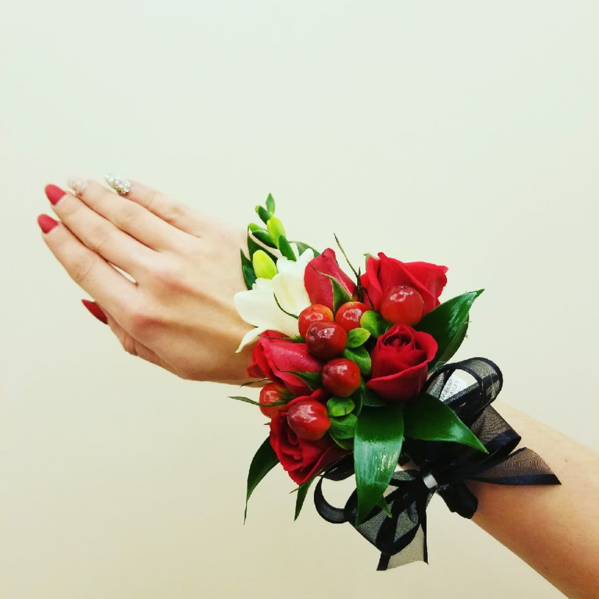 Red rose wrist corsage with white accent flowers and black ribbon