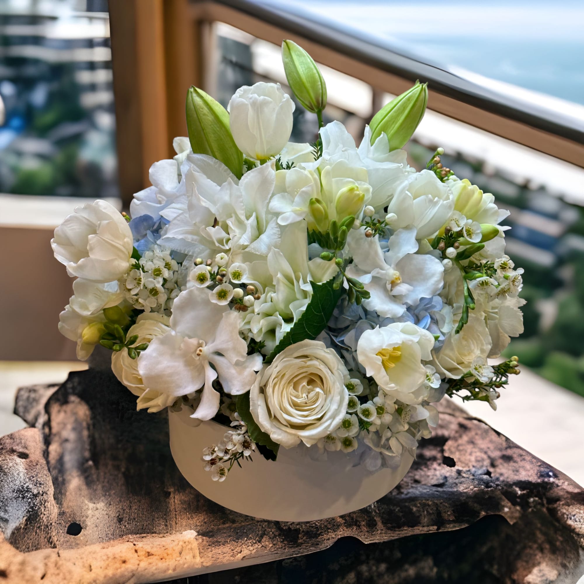 White floral arrangement in a round white container with green buds