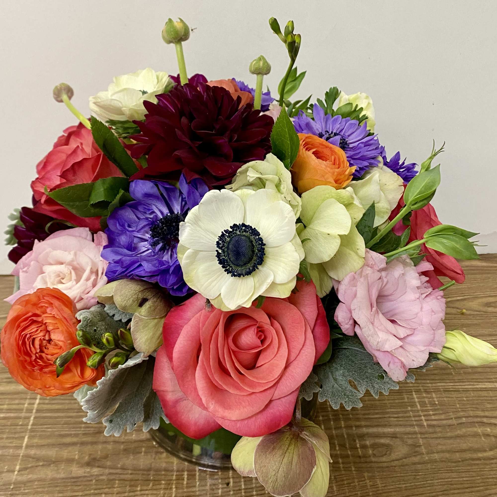 In a clear glass vase combinations of dahlia,  garden roses, tulips