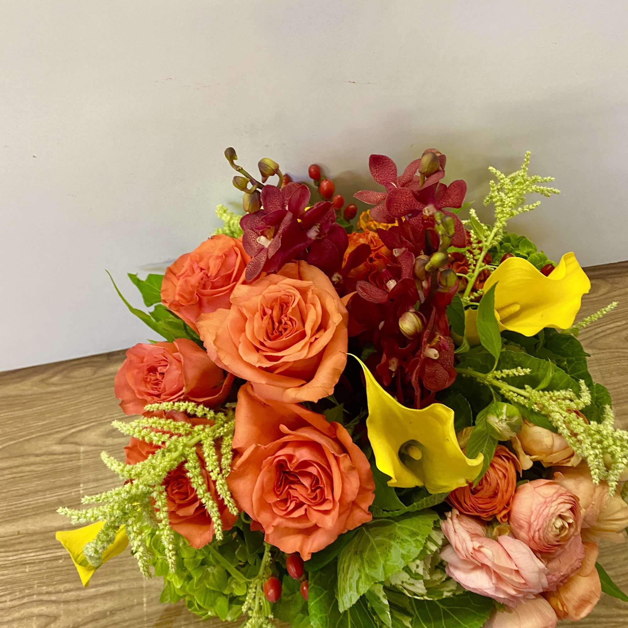 Bouquet of orange roses, yellow calla lilies, and burgundy orchids