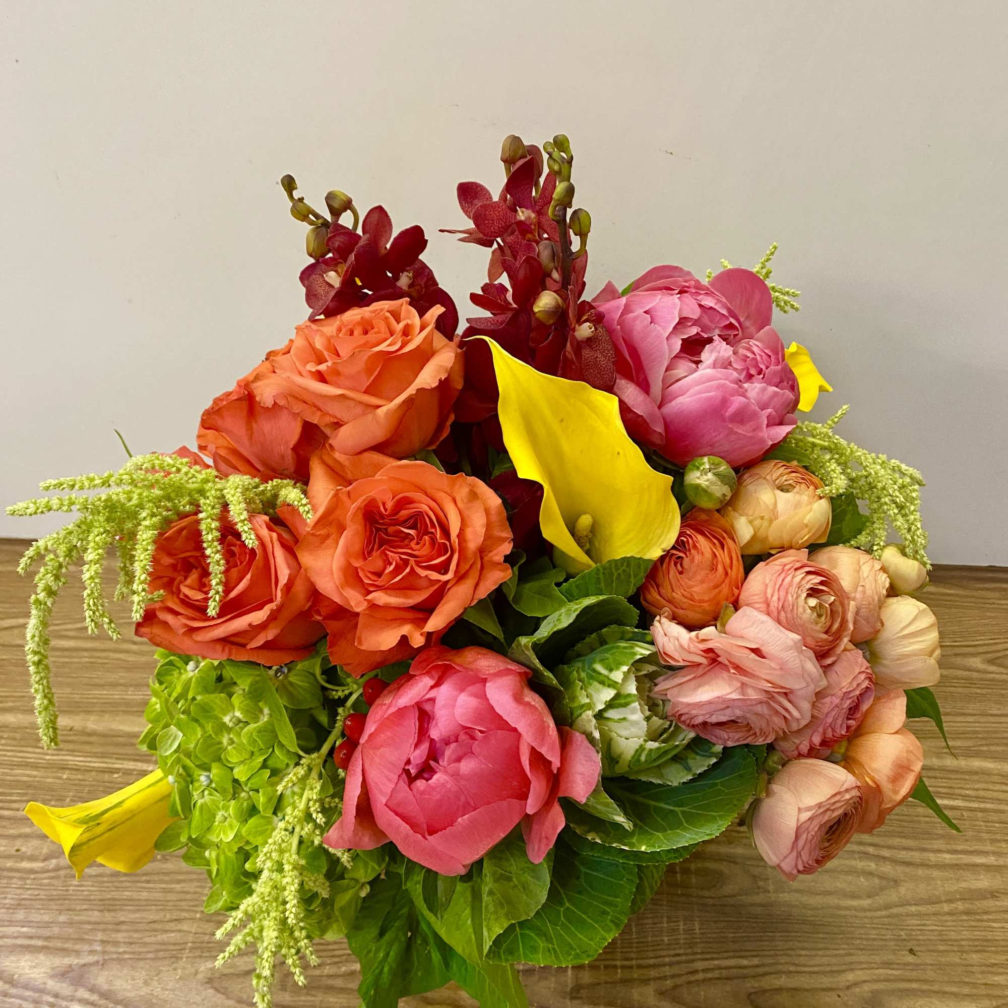 Colorful bouquet with orange roses, pink peonies, yellow calla lilies, and orchids