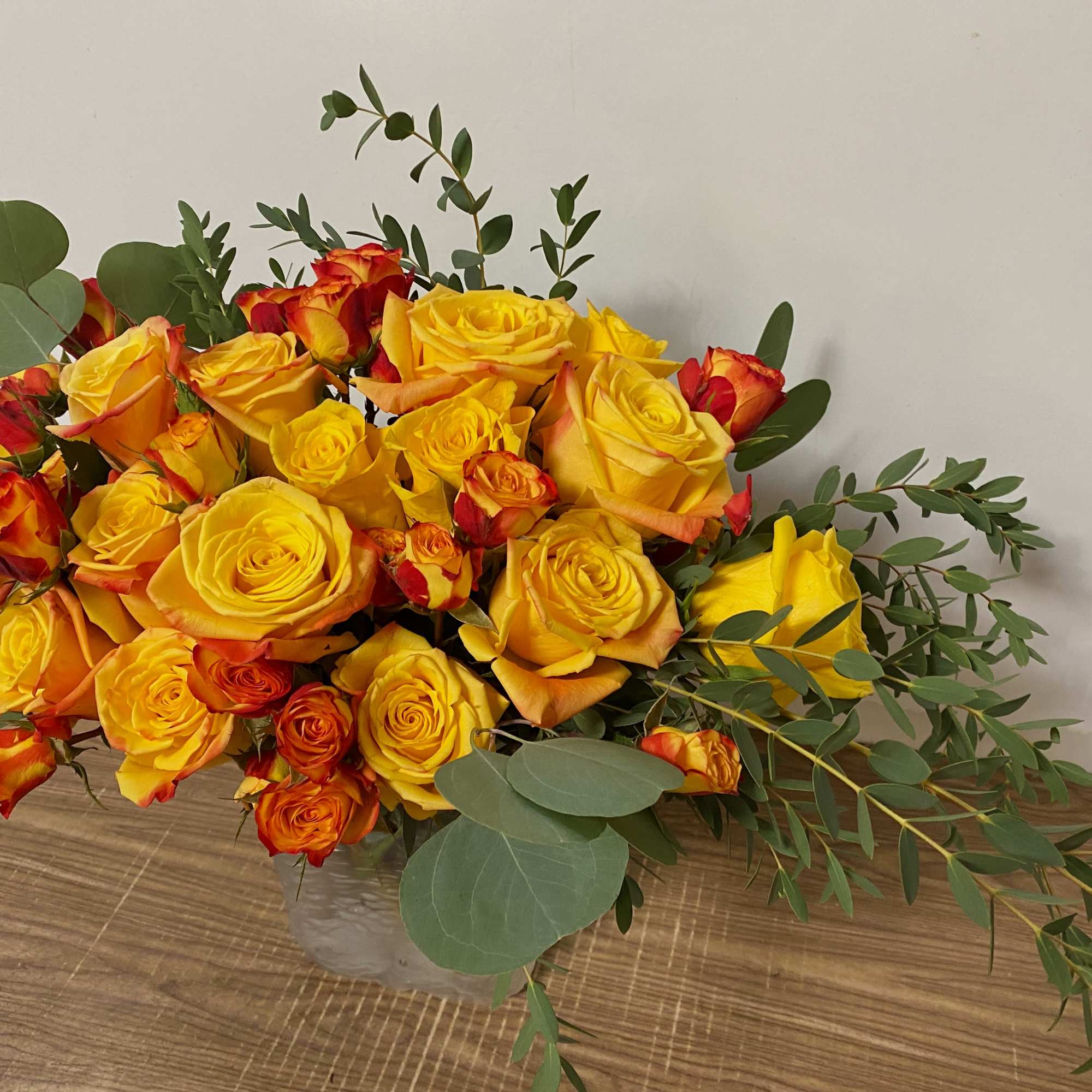 Bouquet of yellow and orange roses in a clear vase