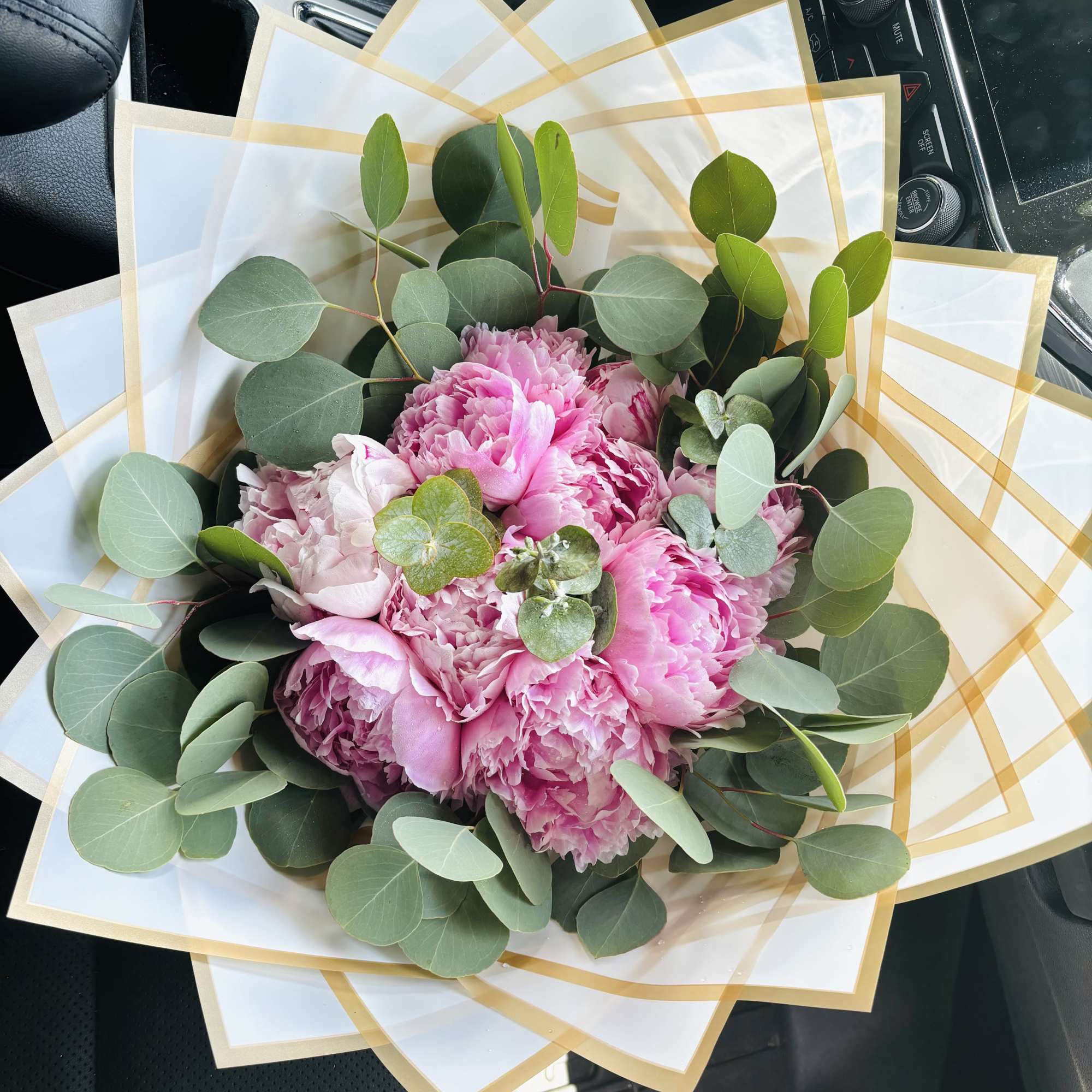 Pink peony bouquet wrapped in white paper with gold trim