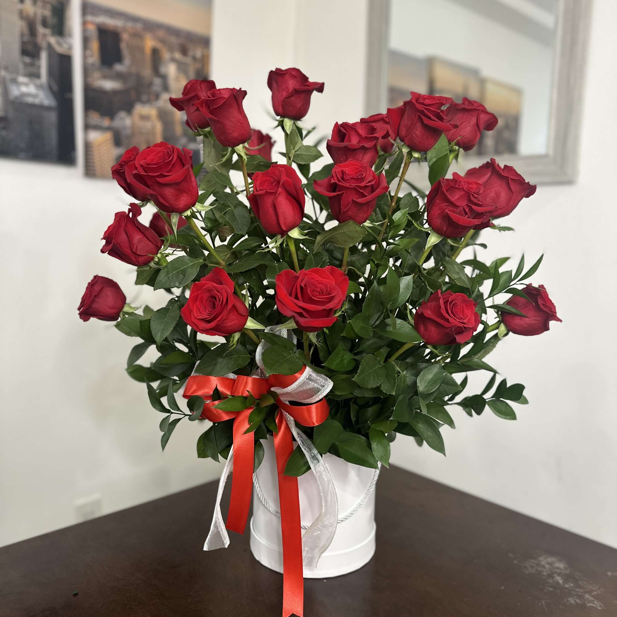 Bouquet of red roses in a white container with red and silver ribbon