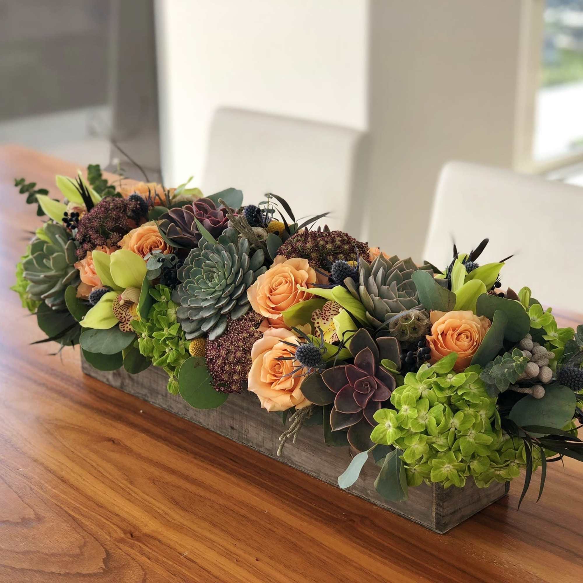 Low rectangular arrangement with peach roses, succulents, and green hydrangeas in a wooden box