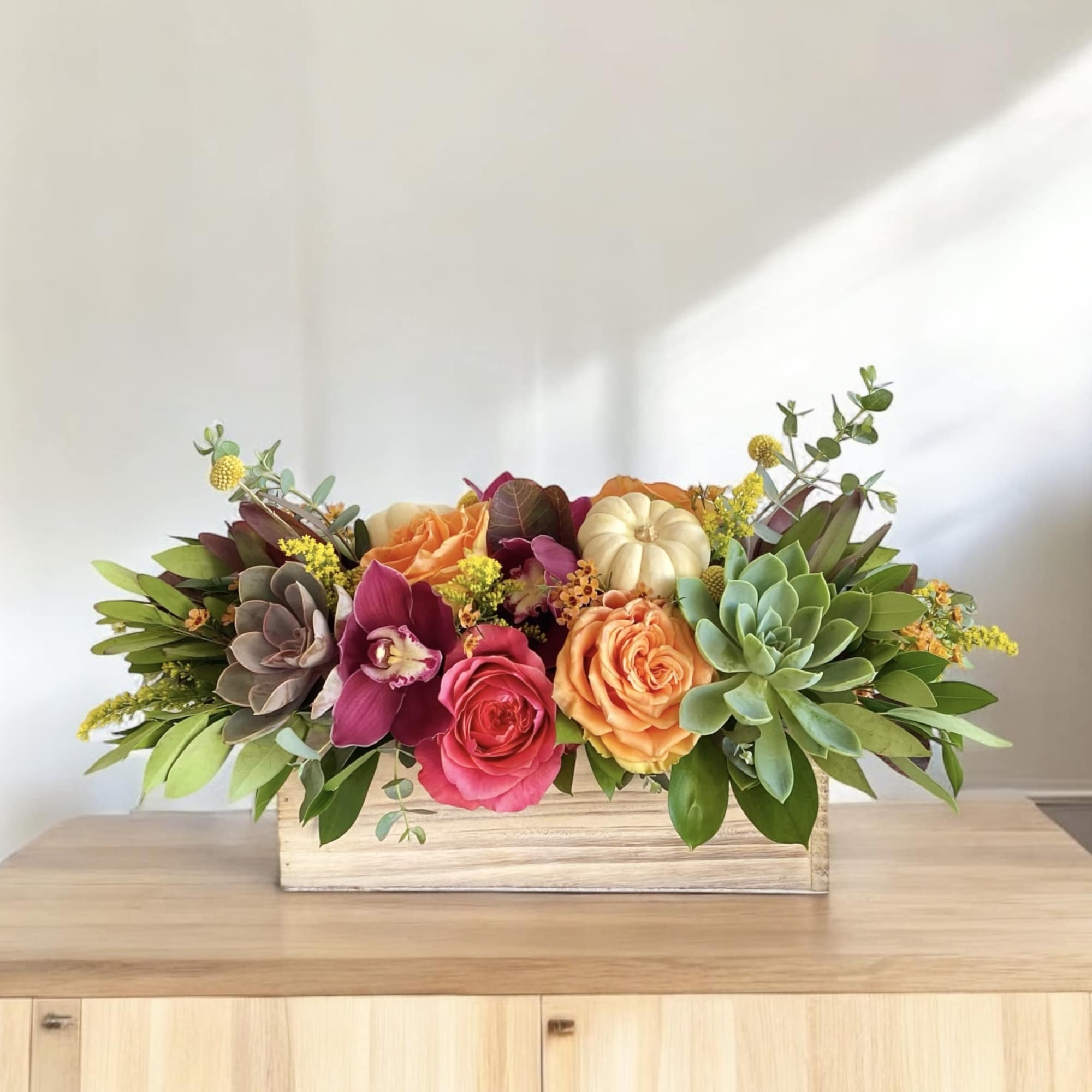 Mixed floral arrangement with roses and succulents in a wooden box