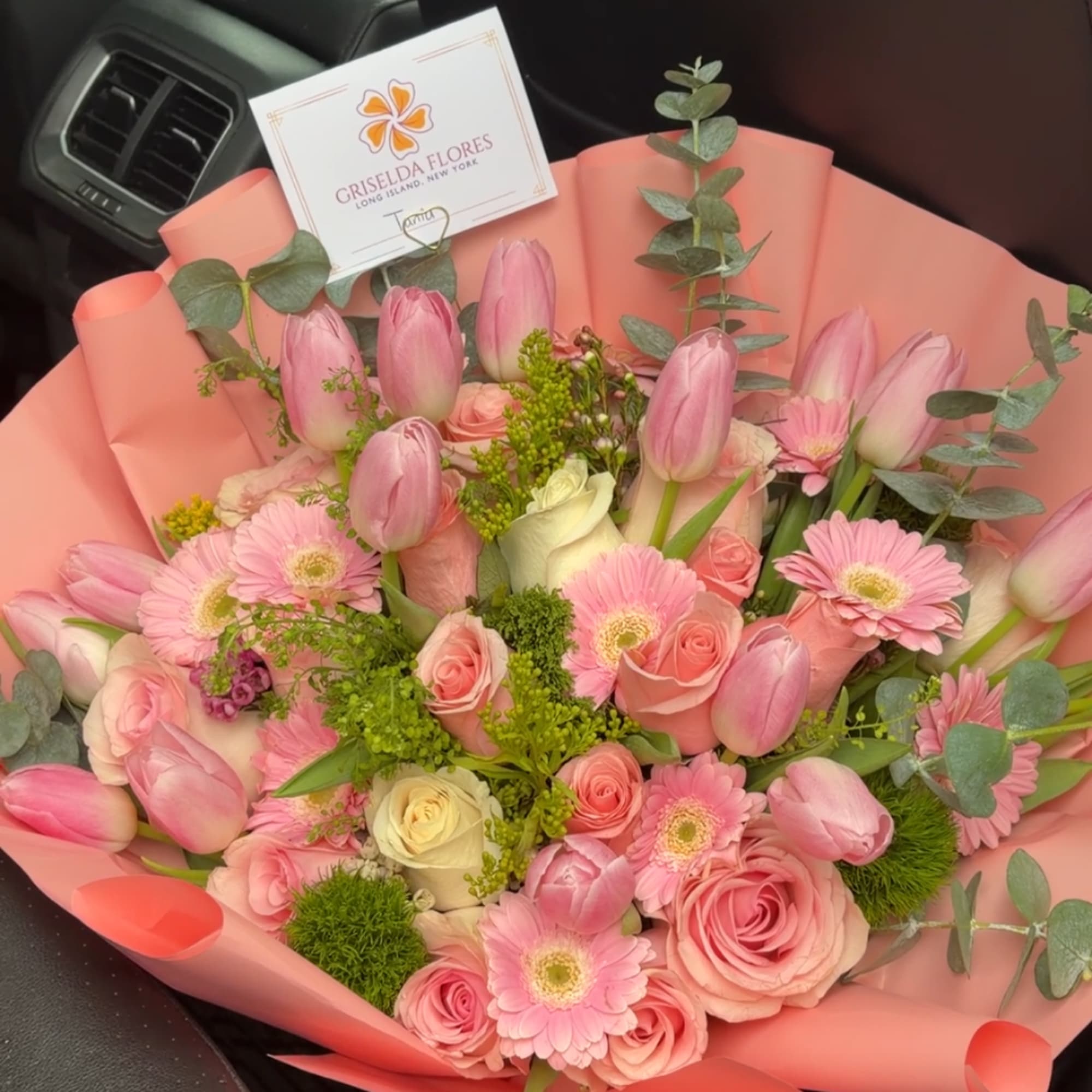 Pink tulips, roses, and gerbera daisies in coral wrapping
