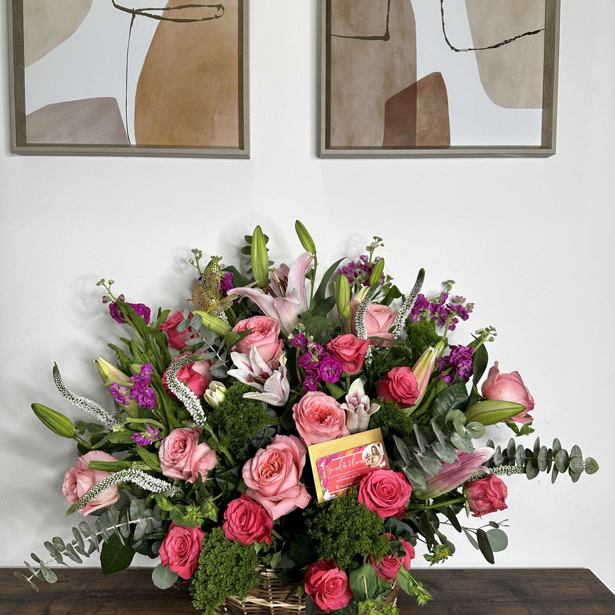 Large basket arrangement of pink roses and lilies with purple accents