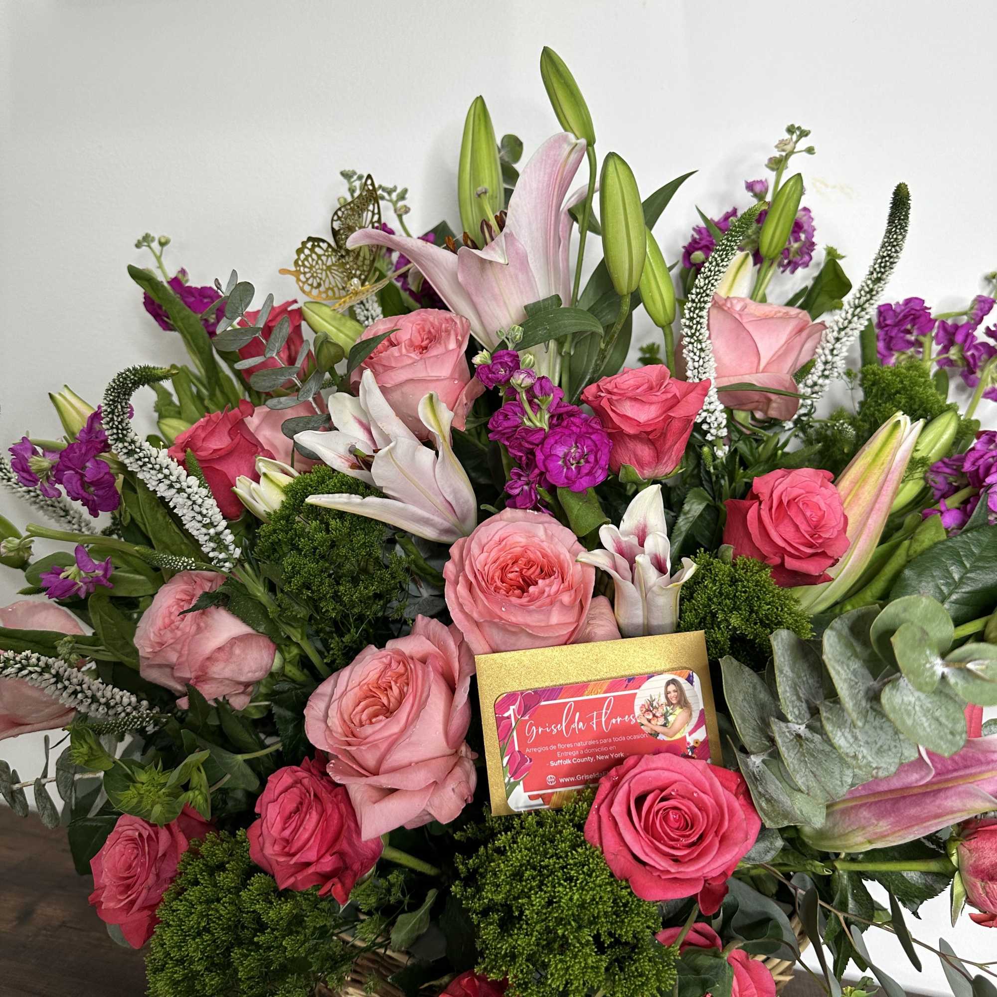 Basket arrangement of pink roses, lilies, and purple flowers