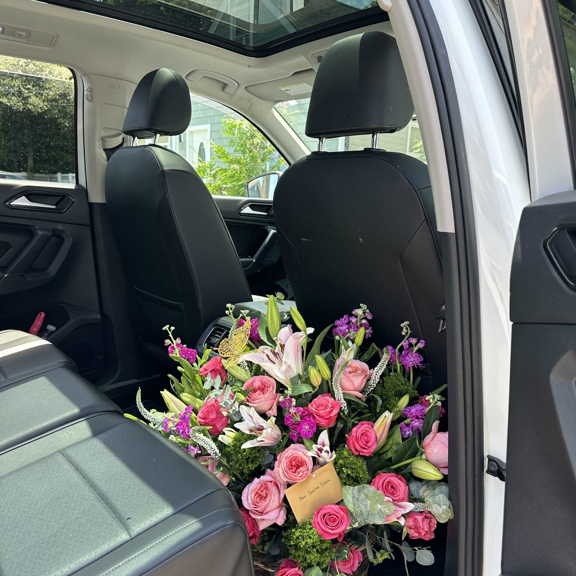 Large basket arrangement of pink roses and lilies in a car interior