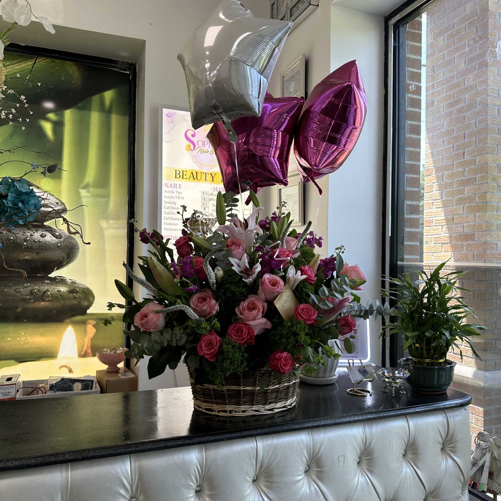 Basket arrangement of pink roses and lilies with metallic balloons