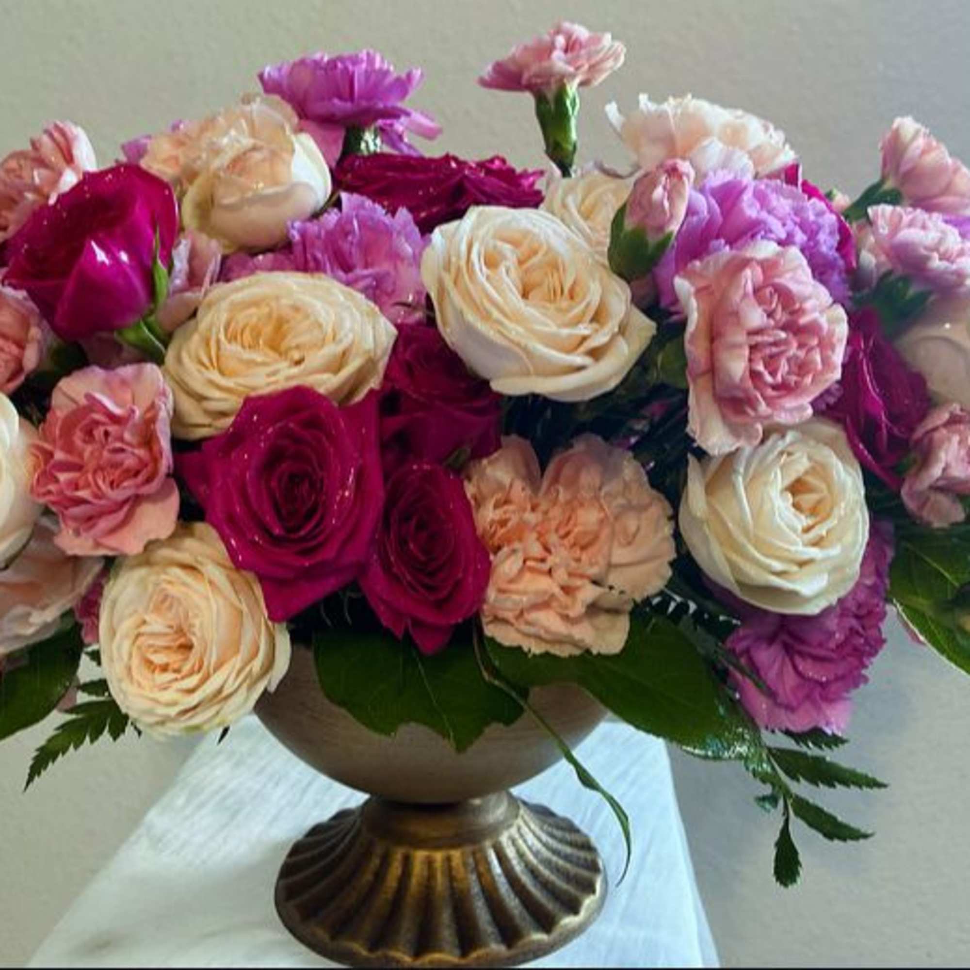 Mixed pink and cream roses arranged in a pedestal vase