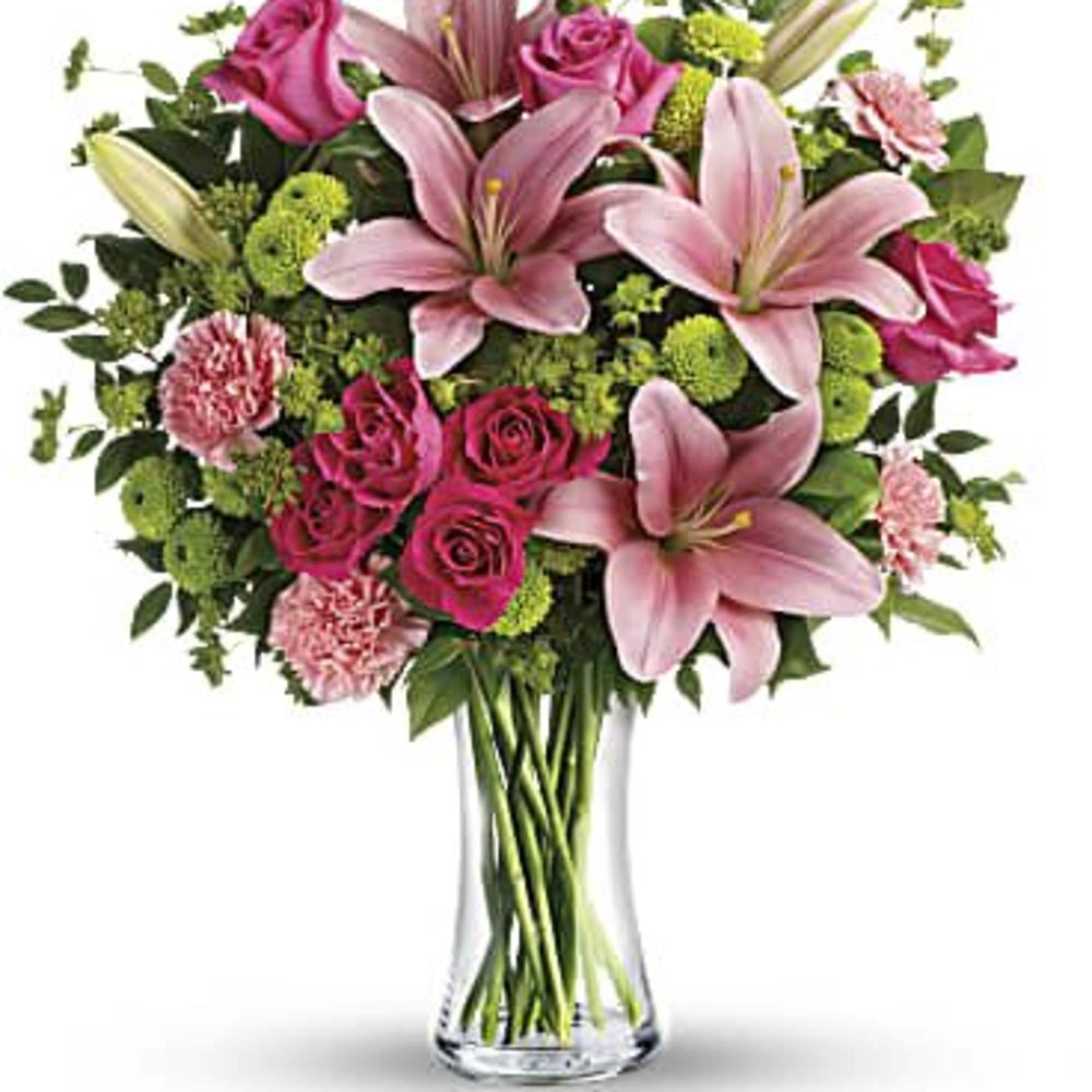 Pink lilies and roses arranged in a clear glass vase