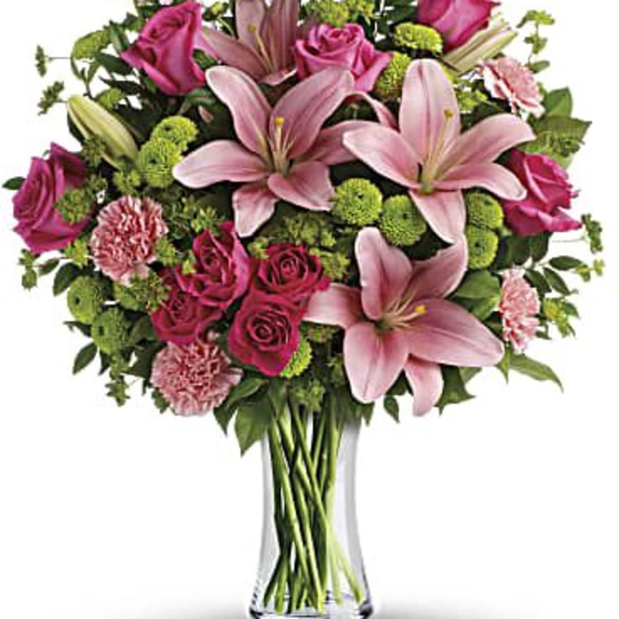 Pink lilies and roses arranged in a clear glass vase