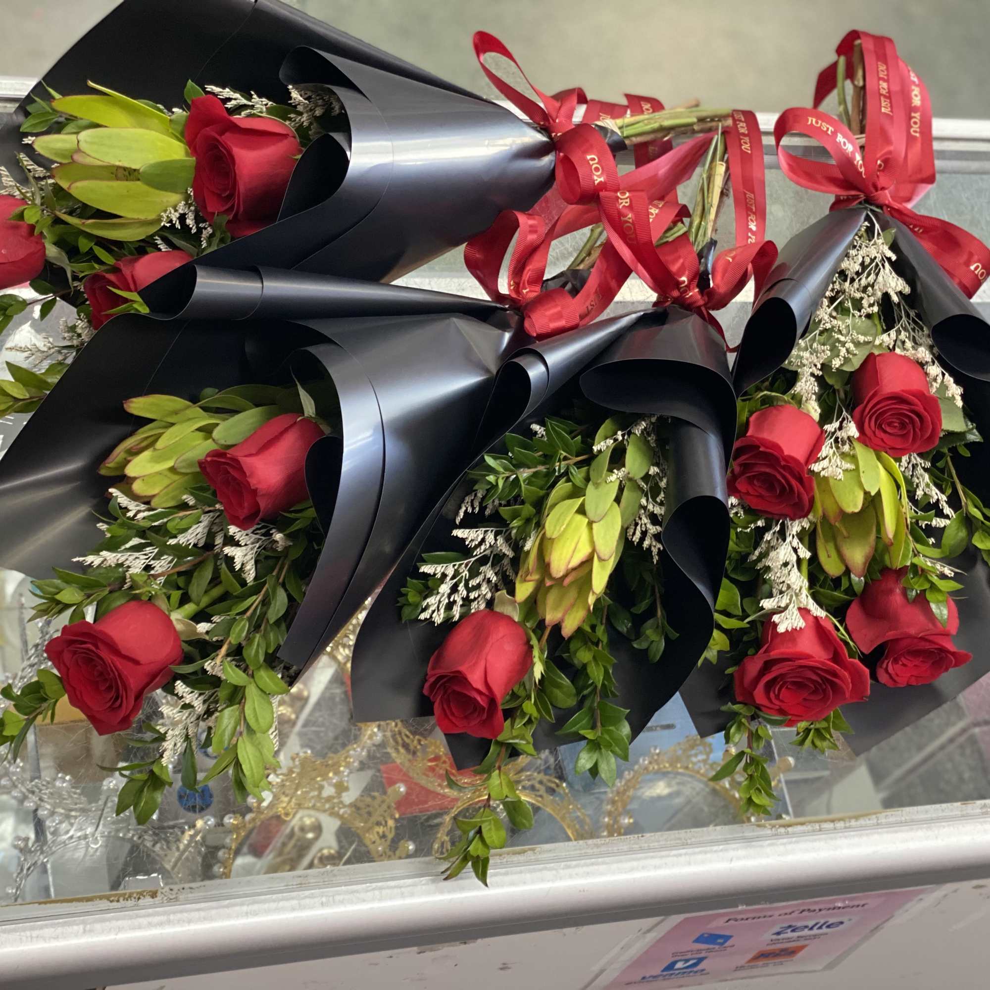 Four red rose bouquets wrapped in black paper with red ribbons