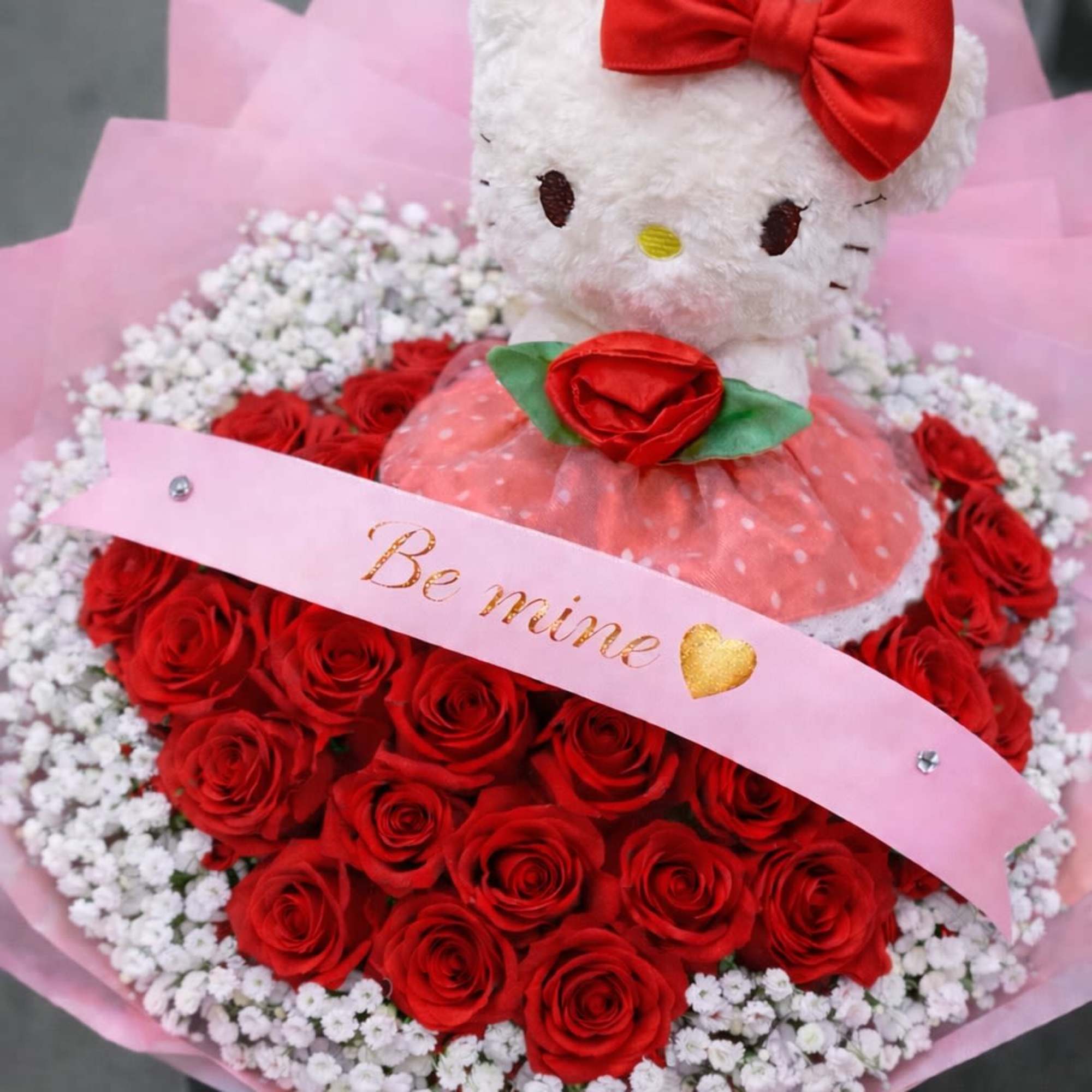 Hello Kitty plush in a bouquet of red roses and white baby's breath