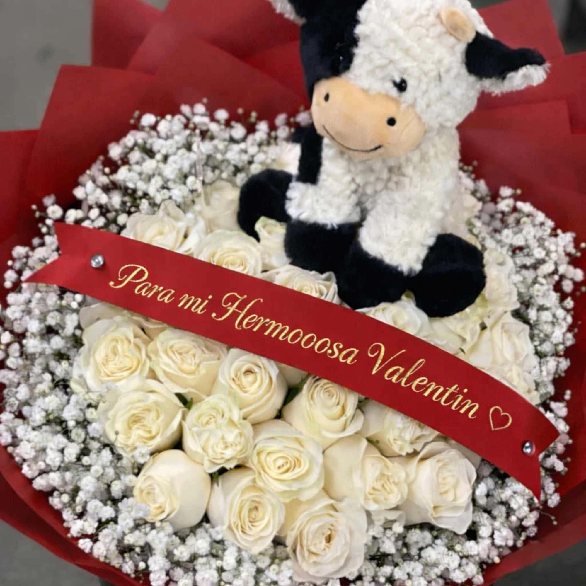 White rose bouquet with baby’s breath and a plush cow topper