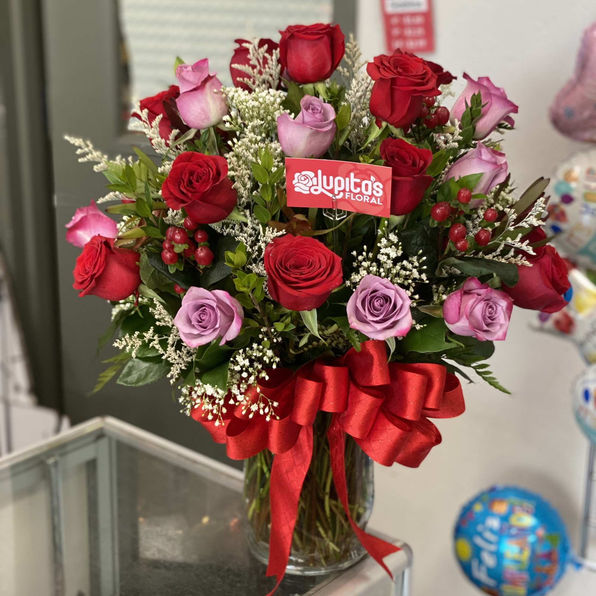 Bouquet of red and lavender roses in a glass vase with a red ribbon