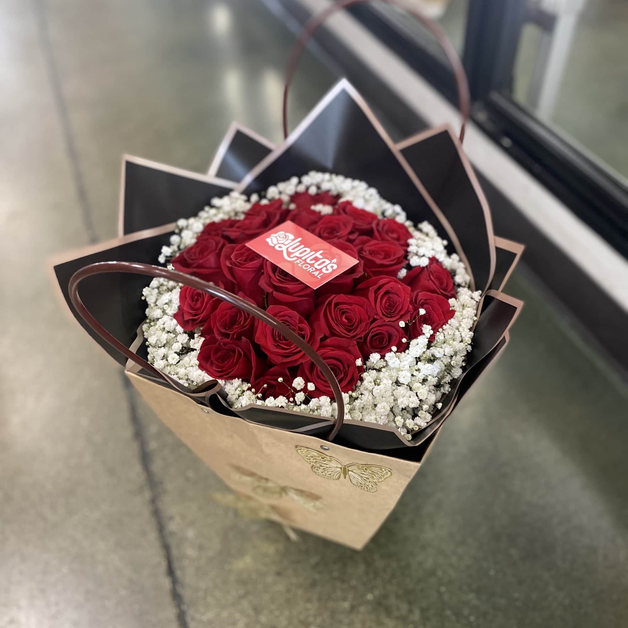 Bouquet of red roses with white baby's breath in a wrapped gift bag