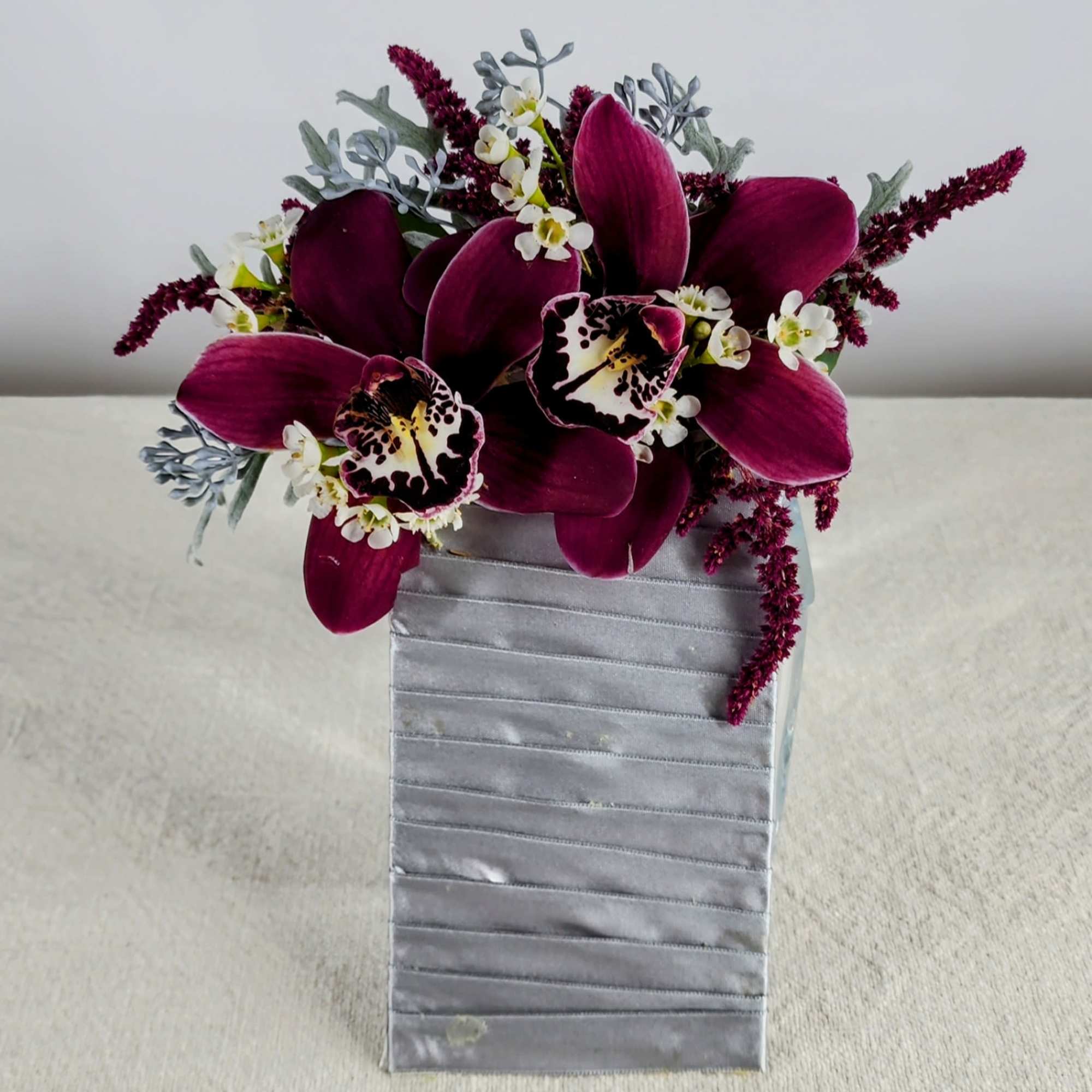Purple orchid arrangement in a silver rectangular vase