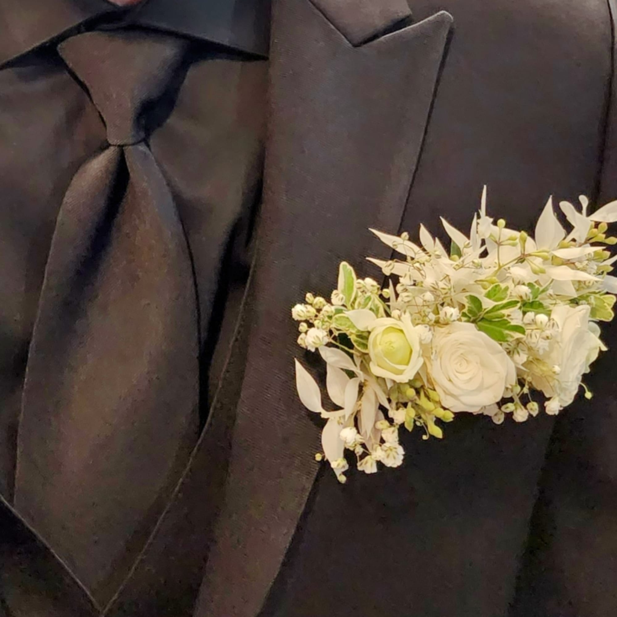 White floral boutonniere on a black suit jacket
