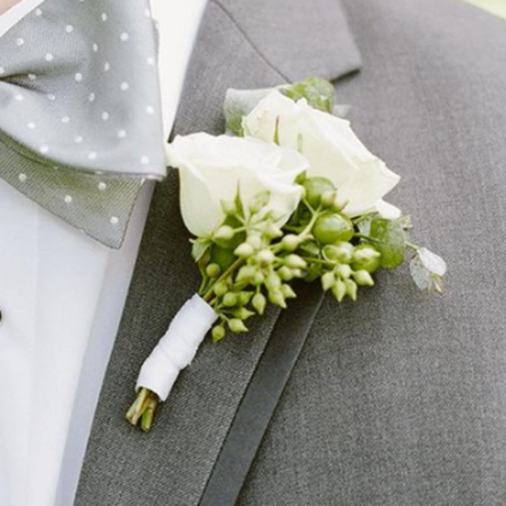 White rose boutonniere pinned to a gray suit jacket