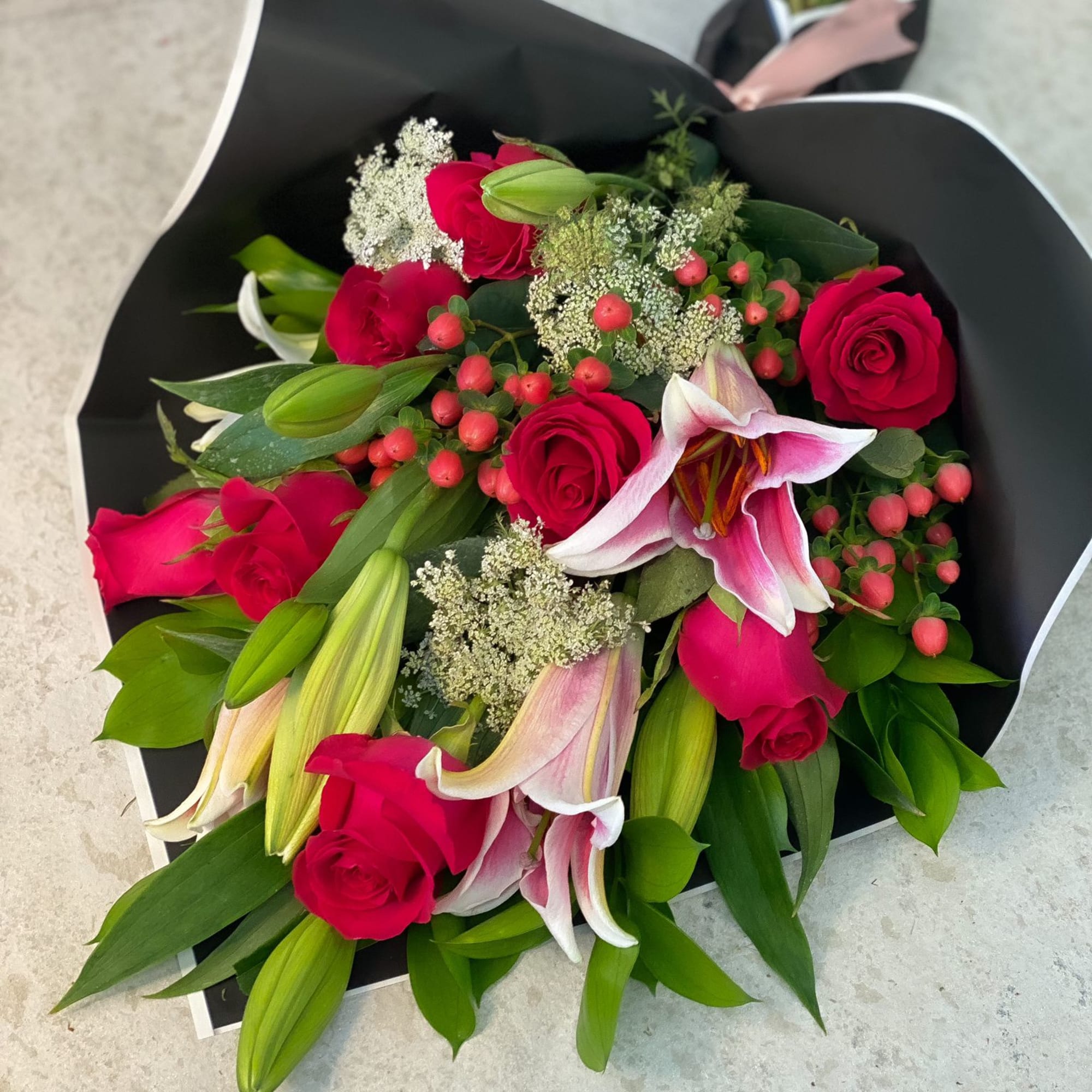 Bouquet of pink roses and lilies wrapped in black paper